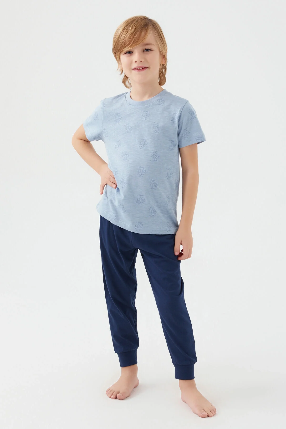 Arnetta Erkek Çocuk Mavi Pijama Takımı, görselde çocuk modelle ön ve yan görünüm, tropikal desenli üst ve koyu mavi pantolon