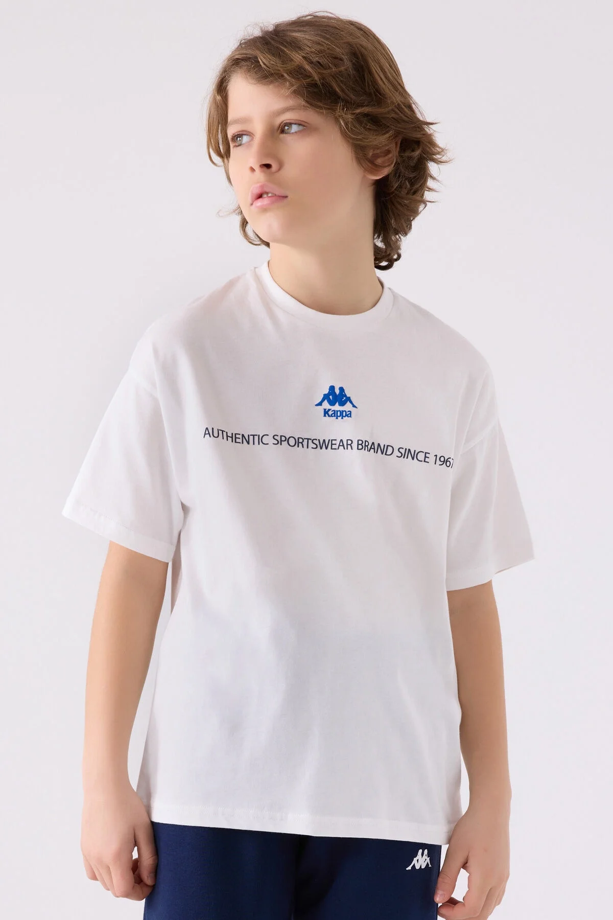 Kappa Erkek Çocuk Beyaz T-Shirt, marka logosu ve 'Authentic Sportswear' yazısı, çocuk modeli ön görünümü