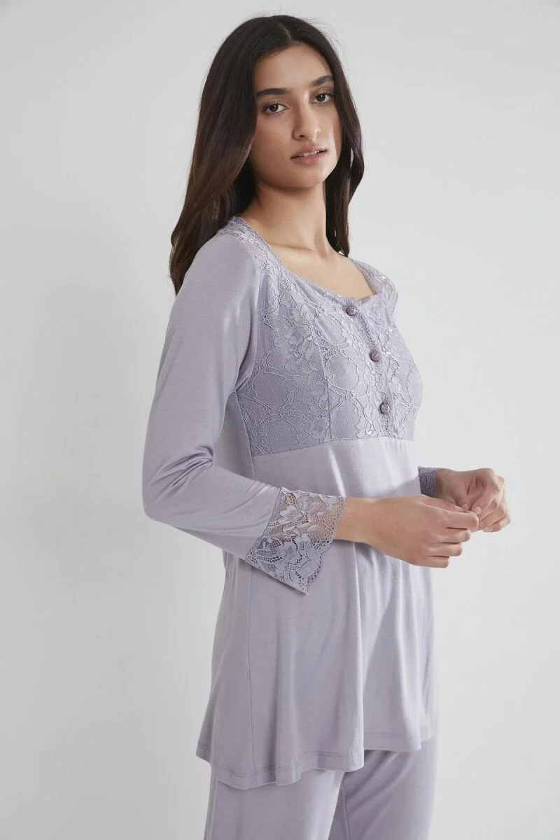 Lavanta rengi dantelli lohusa pijama takımını giyen kadın, Pierre Cardin markası, üstü dantel detaylı, pantolonu geniş kesimli, beyaz arka plan
