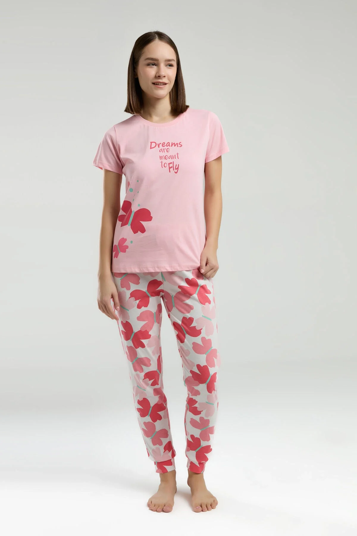 Pembe kadının pijama takımı, Arnetta markası, görselde 'Dreams are meant to Fly' yazısı ve kırmızı kalp desenli pantolonlar