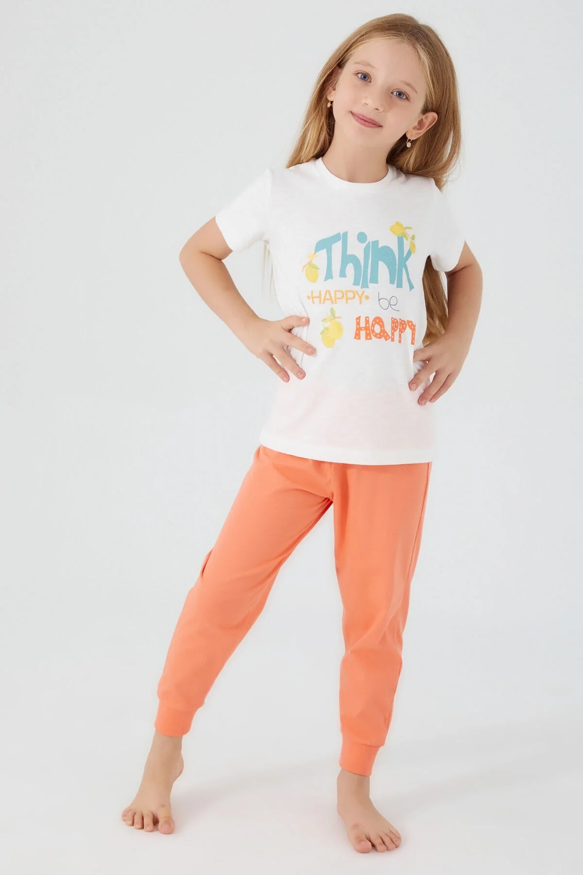 Beyaz ve turuncu renkli kız çocuk pijama takımı, 'Think Happy' yazısı ve limon deseni, Arnetta markası, tam vücut görünümü
