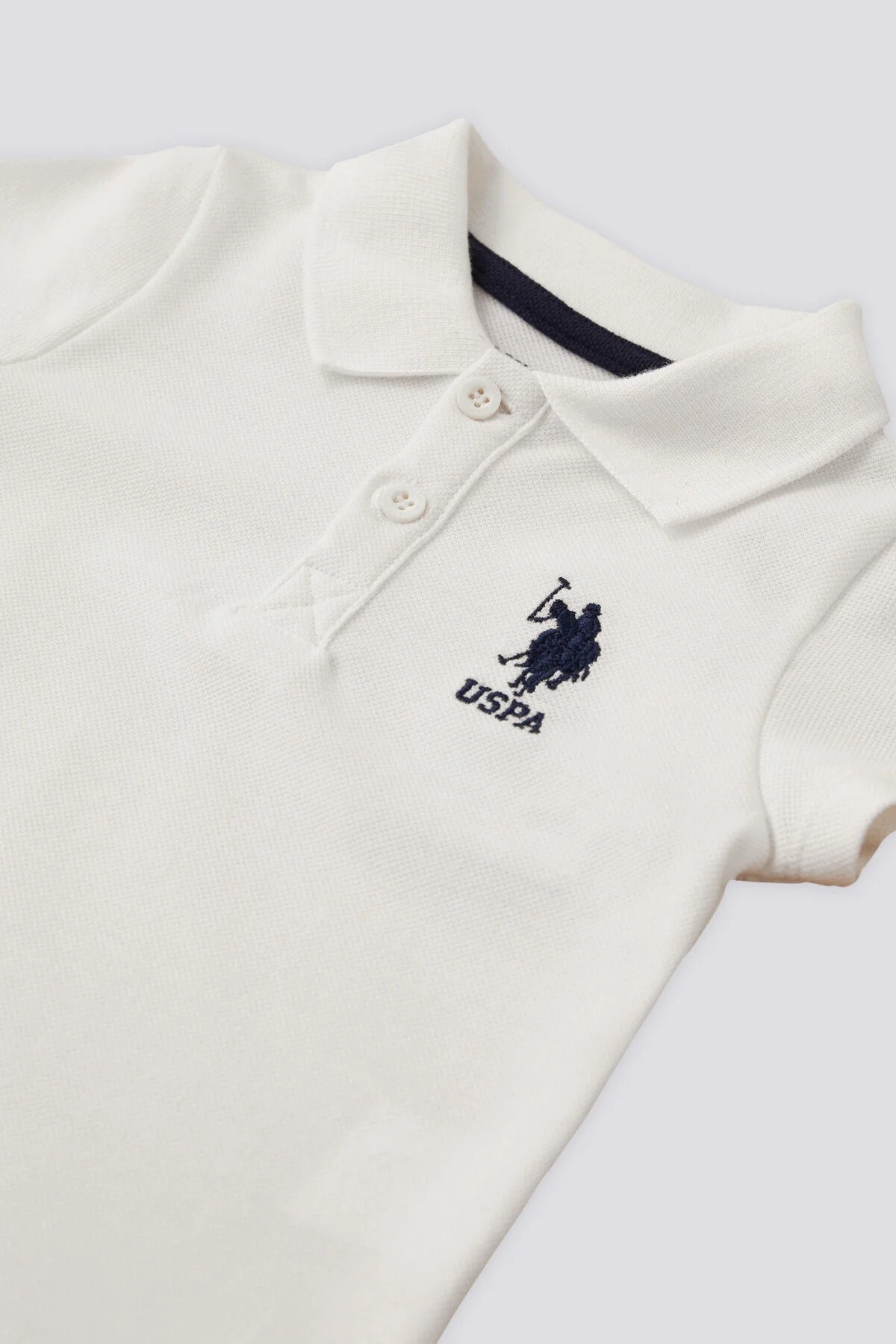 Beyaz U.S. Polo Assn erkek bebek takım elbette, kısa kollu polo üst ve siyah kısa pantolon, marka logosu ile bebek giyim seti