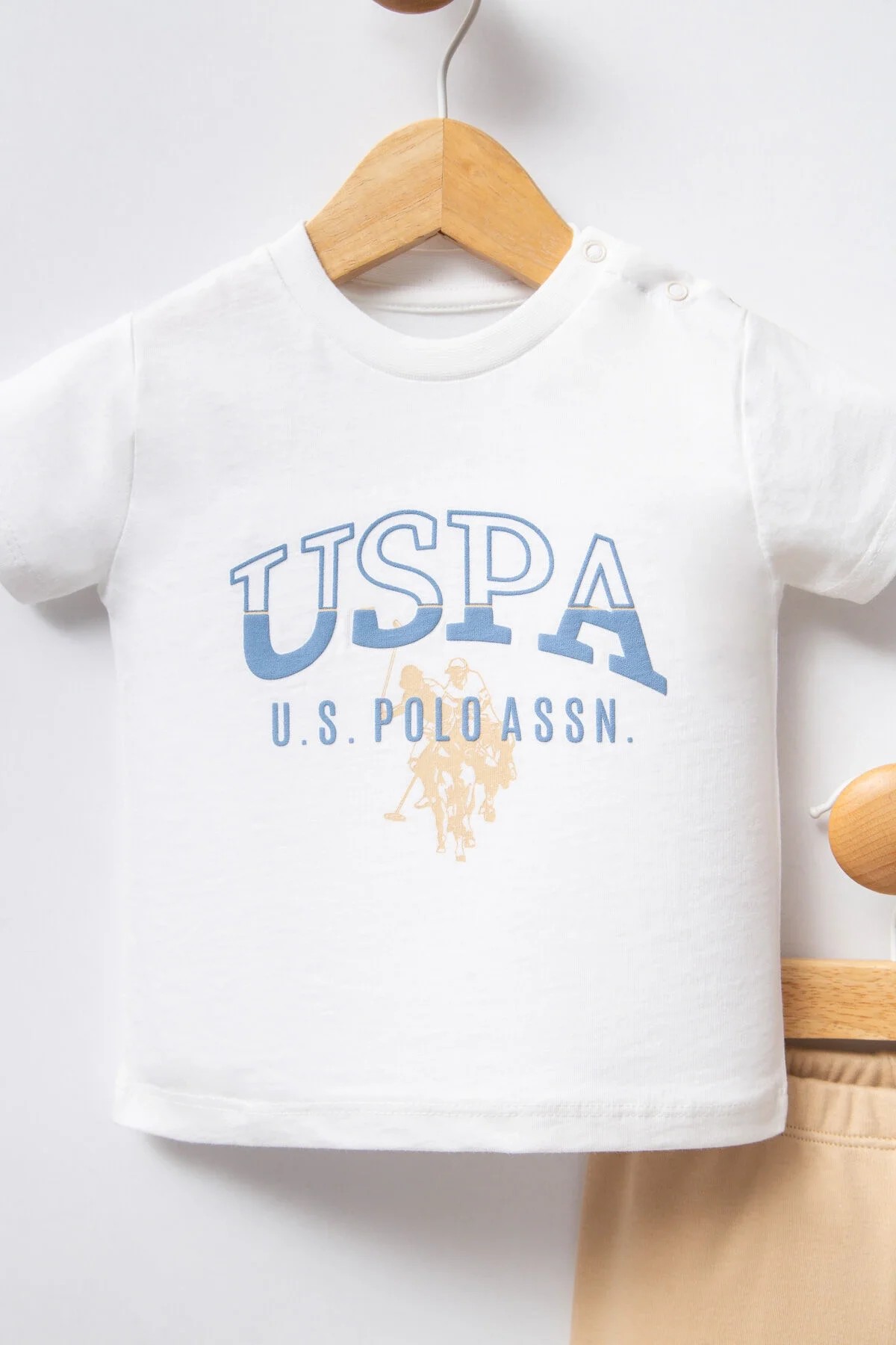 Beyaz USPA logosu olan erkek bebek takımlı set, kremi pantolon ve tişört, bebek giyim kıyafetleri