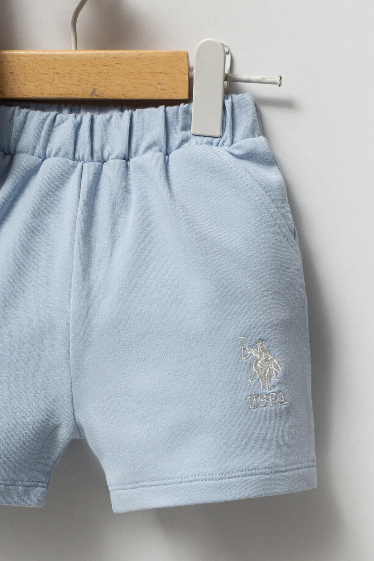Beyaz U.S. Polo Assn erkek bebek takım elbette, mavi şortlu, marka logosu, bebek giyim seti