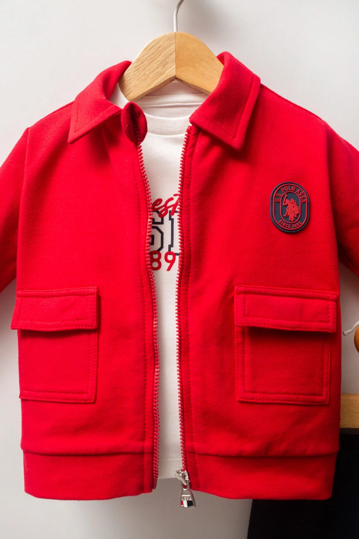 Kırmızı ceket ve mavi pantolonlu U.S. Polo Assn bebek takım elbette, marka logosu ile çocuk giyim seti