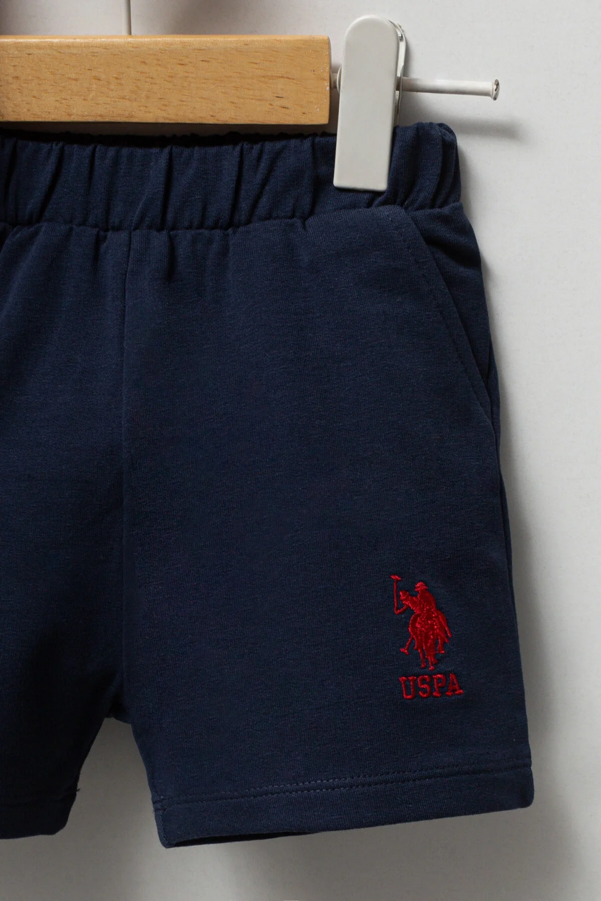 Kırmızı U.S. Polo Assn bebek takım elbette, koyu mavi kısa pantolonlu, marka logosu ile çocuk giyim seti