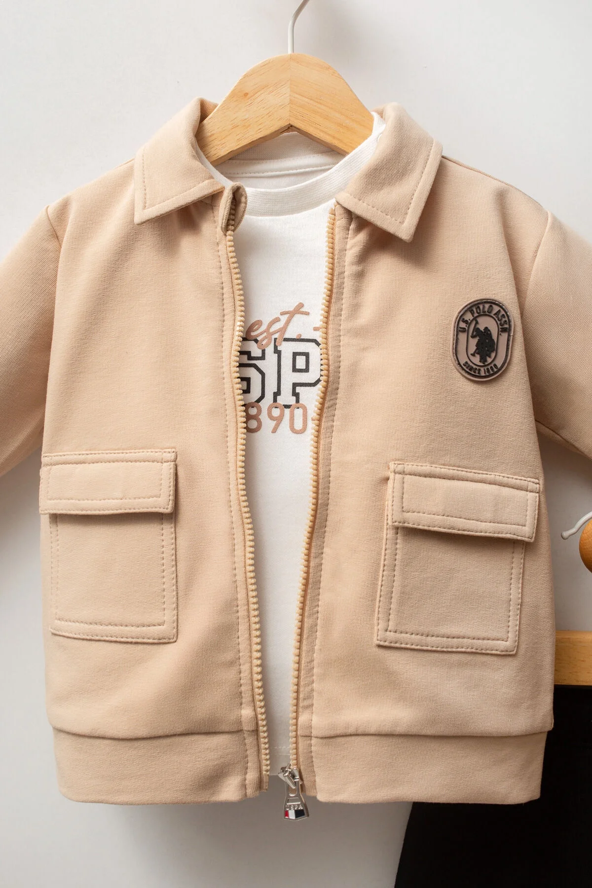 Krem renkli ceket ve siyah pantolonlu U.S. Polo Assn bebek takım elbette, marka logosu ile çocuk giyim seti