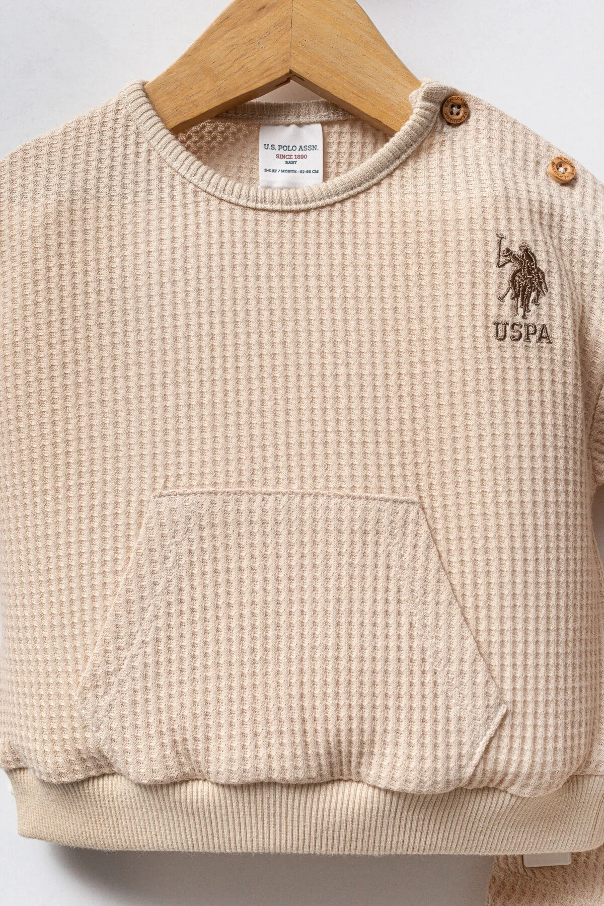 Krem renkli U.S. Polo Assn bebek takım elbette, krem waffle dokulu üst ve pantolon, marka logosu ile bebek giyim seti