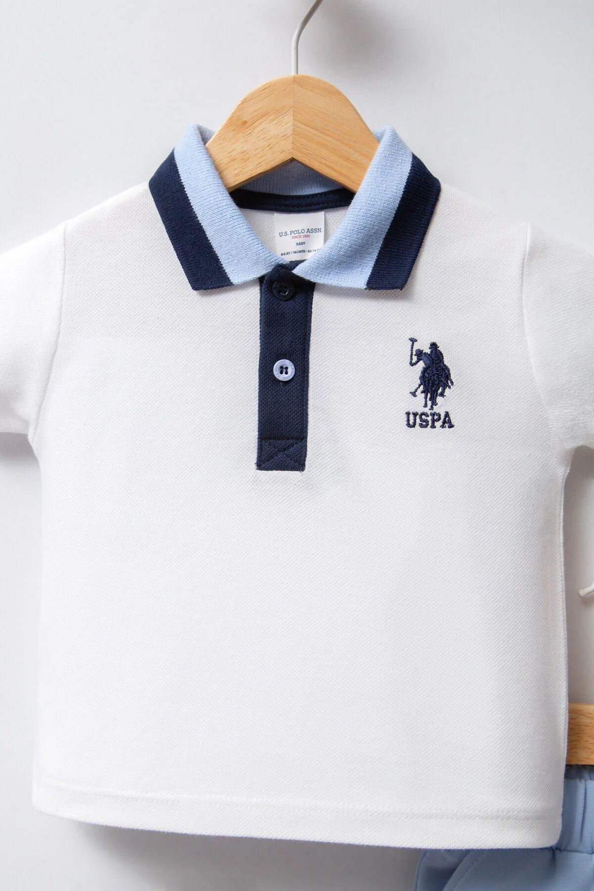 Mavi ve beyaz U.S. Polo Assn bebek takım elbise, erkek bebek giyim seti, marka logosu, hafif renk tonları, temiz arka plan