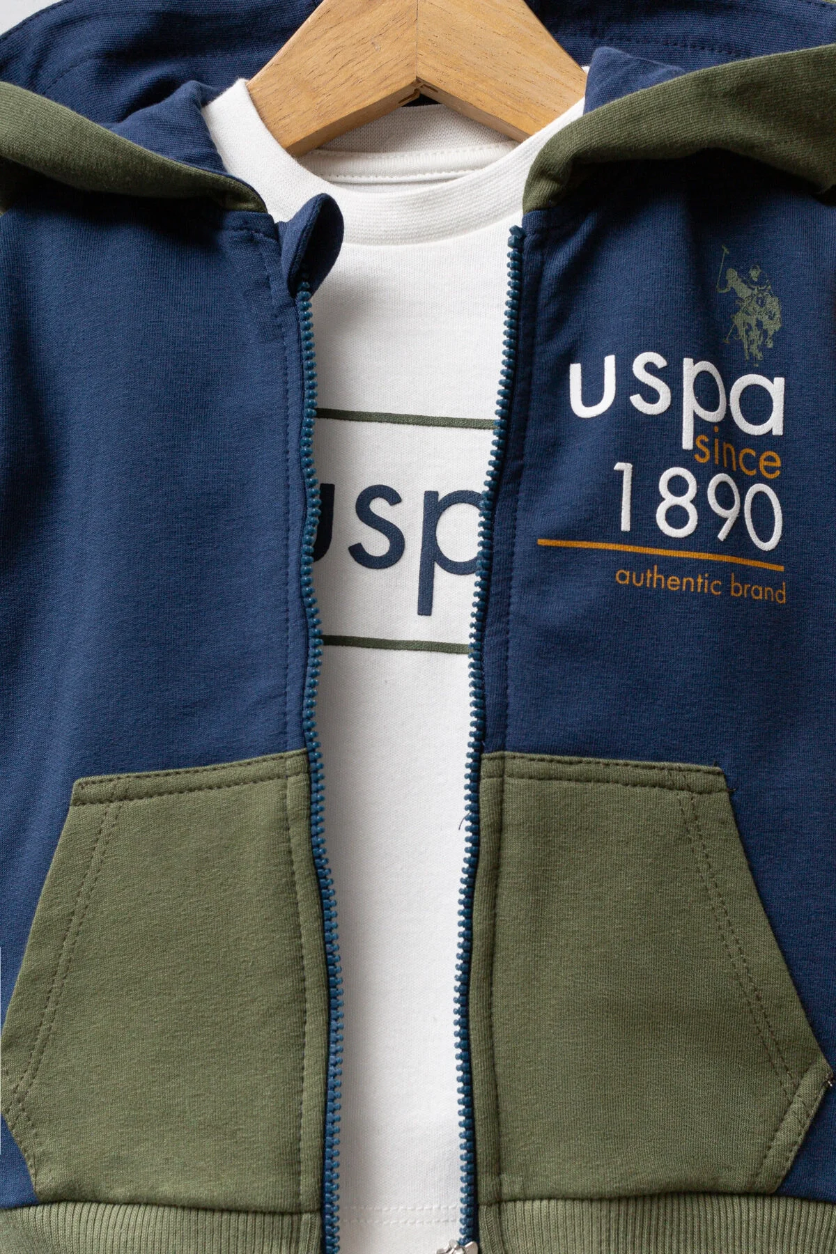 Mavi ve kahverengi detaylı U.S. Polo Assn bebek takım elbise, kapüşonlu ceket ve pantolon, marka logosuyla çocuk giyim seti