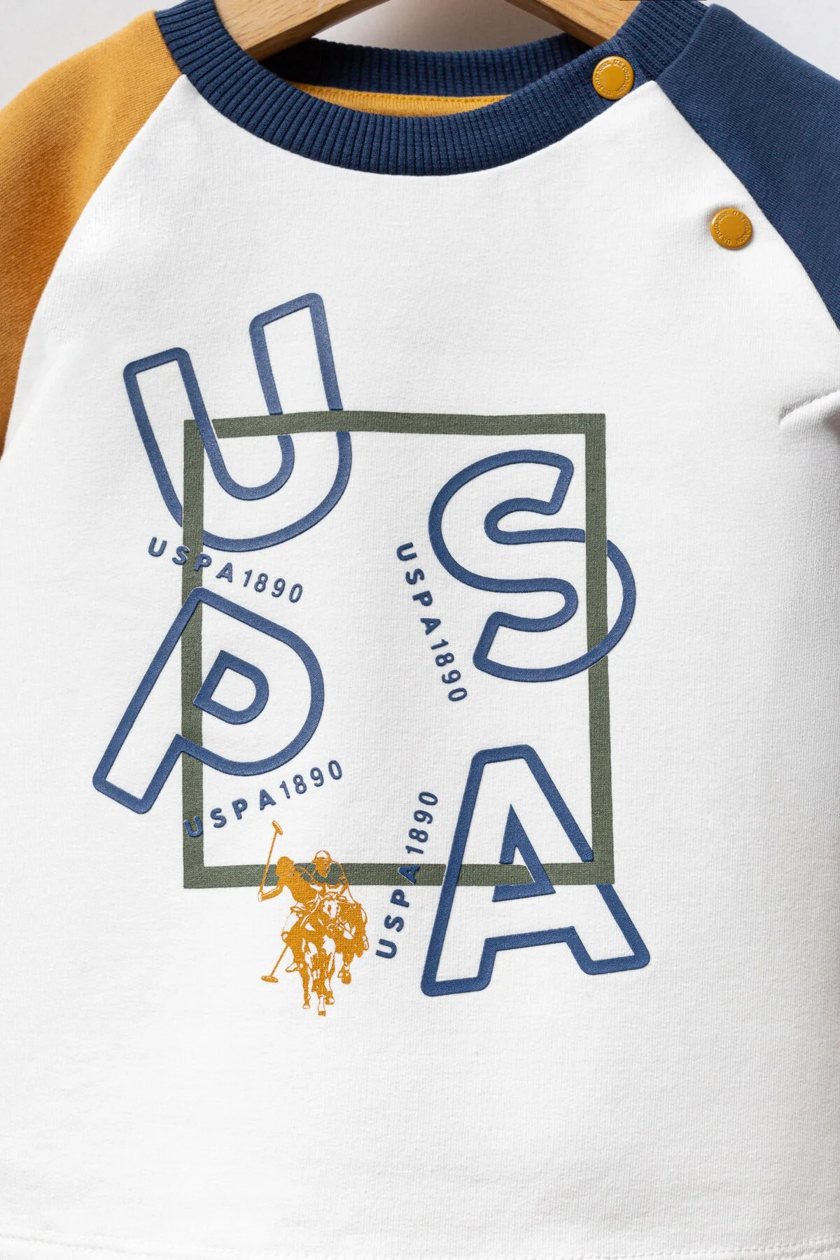 Sarı ve mavi detaylı U.S. Polo Assn bebek takım elbise, beyaz gömlek ve kahverengi pantolon, marka logosu ile çocuk giyim seti