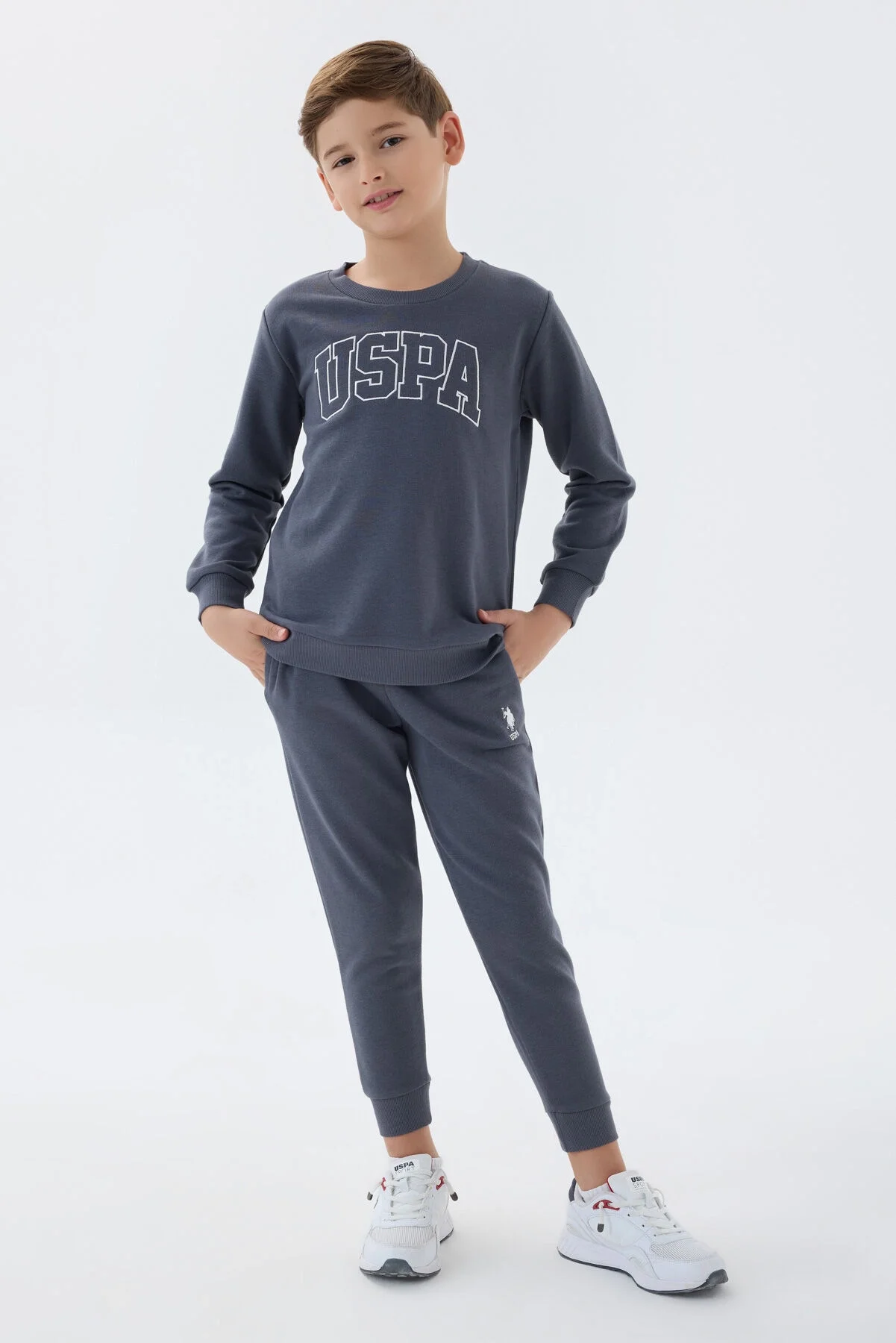 Antrasit renkli U.S. Polo Assn erkek çocuk eşofman takımı, üstte büyük harfli USPA yazısı, pantolonun ön cebinde marka logosu