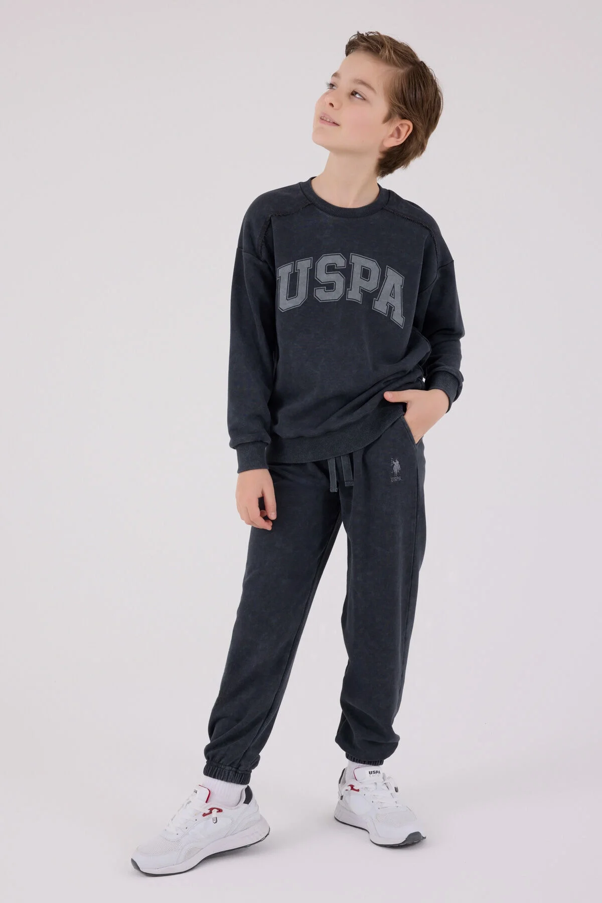 Antrasit renkli U.S. Polo Assn erkek çocuk eşofman takımı, üstte 'USPA' yazısı, çocuk modeli, spor stil, beyaz arka plan