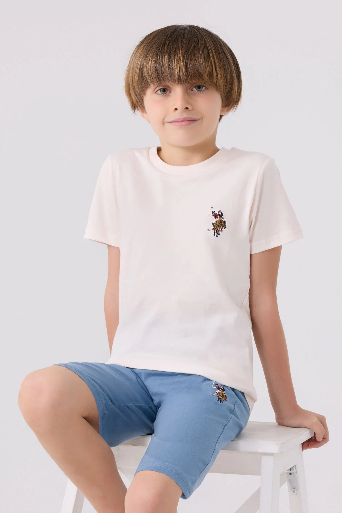Beyaz üst ve mavi Bermuda kısa pantolonlu U.S. Polo Assn erkek çocuk takım elbise, marka logosu detaylı