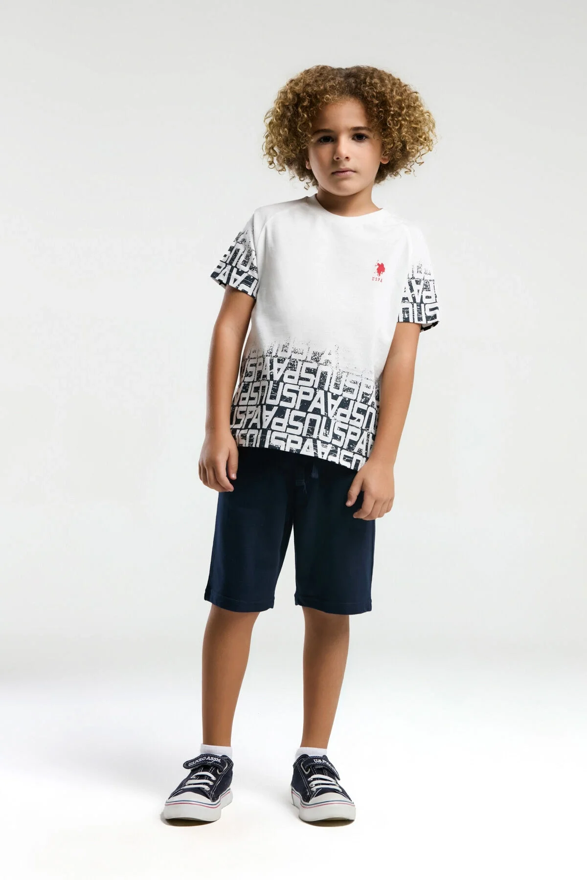Beyaz U.S. Polo Assn erkek çocuk Bermuda takım elbette, marka logosu ve yazı deseniyle modern çocuk giyim