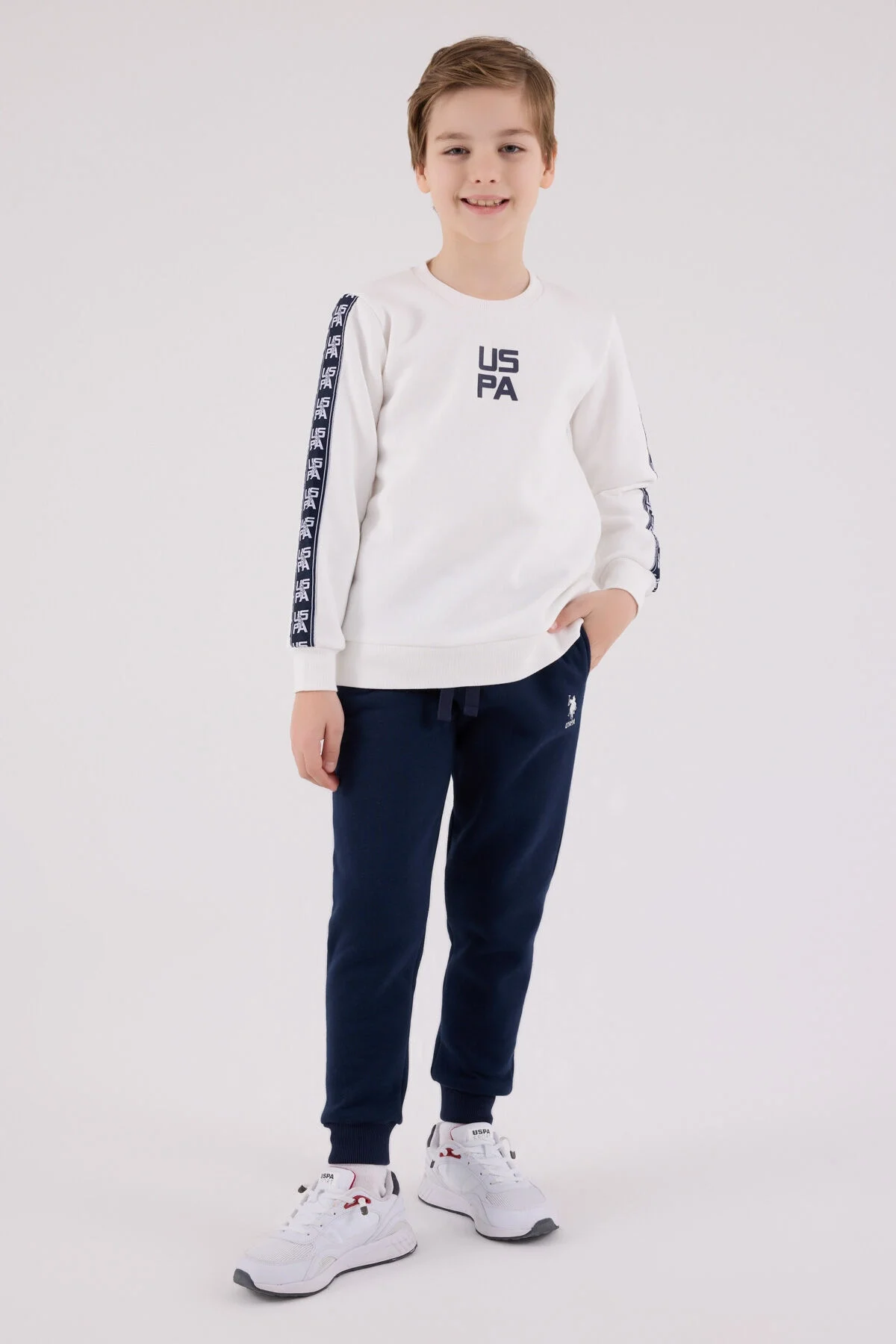 Beyaz USPA logosu ve kollu desenli uzun kollu sweatshirt ile mavi eşofman takımı, erkek çocuk giyim modeli