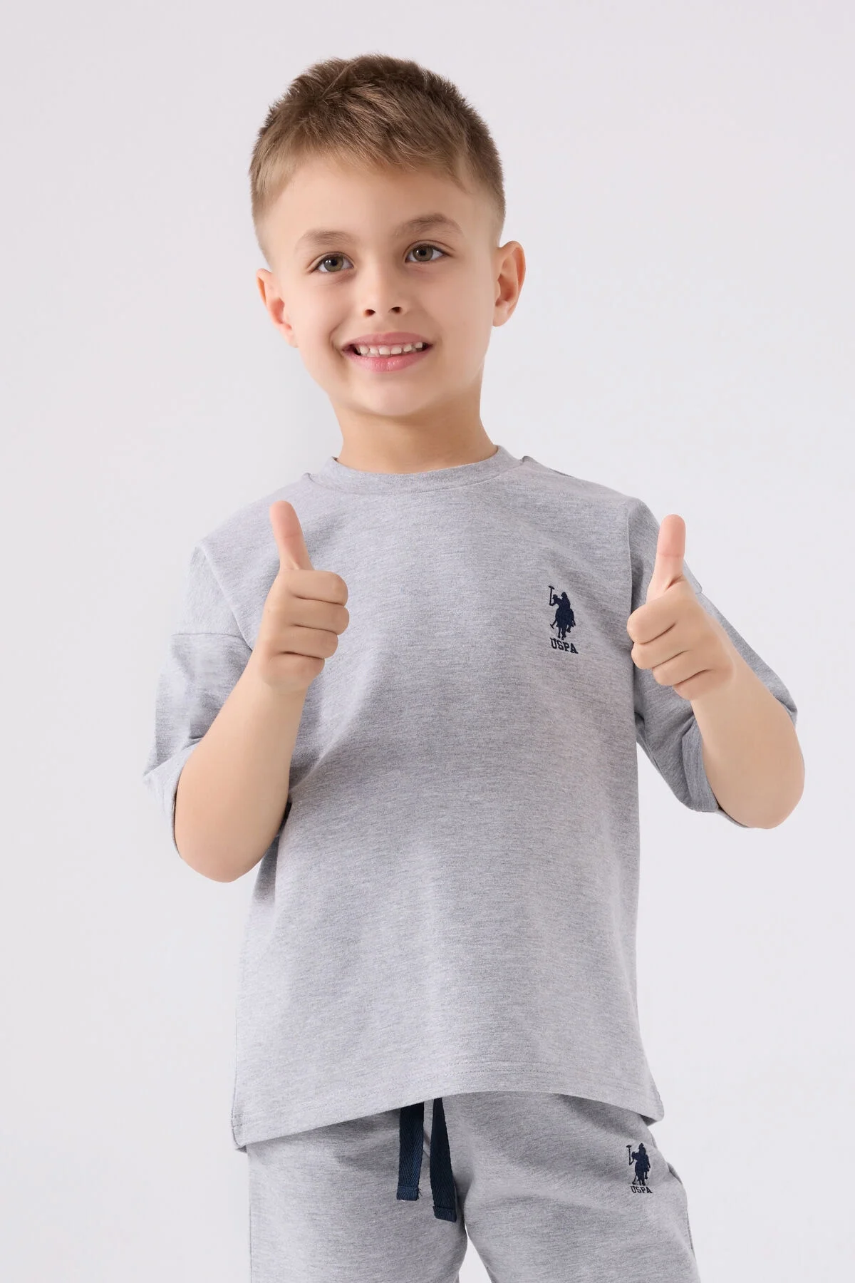 Gri U.S. Polo Assn Erkek Çocuk Bermuda Takım, çocuk modeli ön görünüm, marka logosu ve spor ayakkabılarla tamamlandı