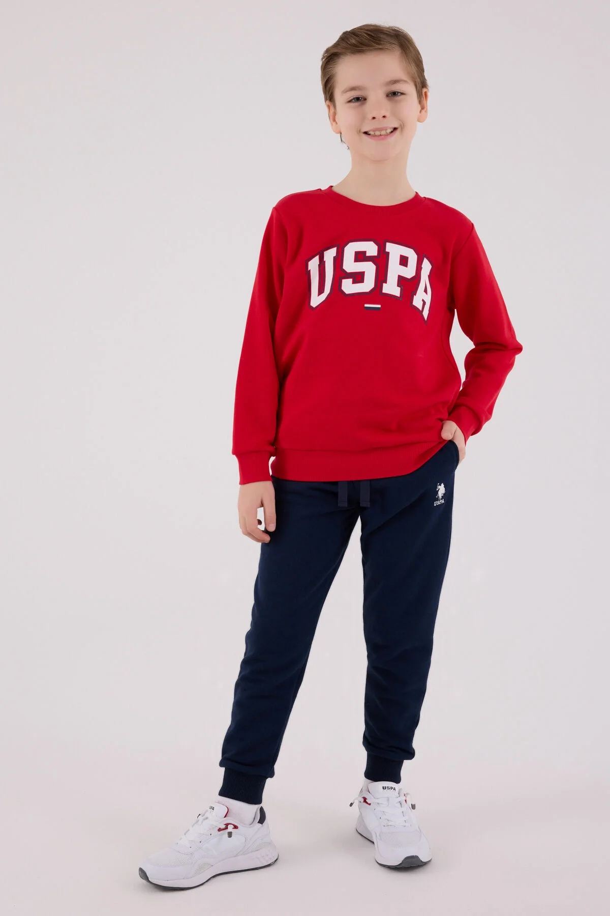 Kırmızı USPA yazısı olan erkek çocuk eşofman takımı, mavi pantolonlu, çocuk modeli, spor stil, beyaz arka plan