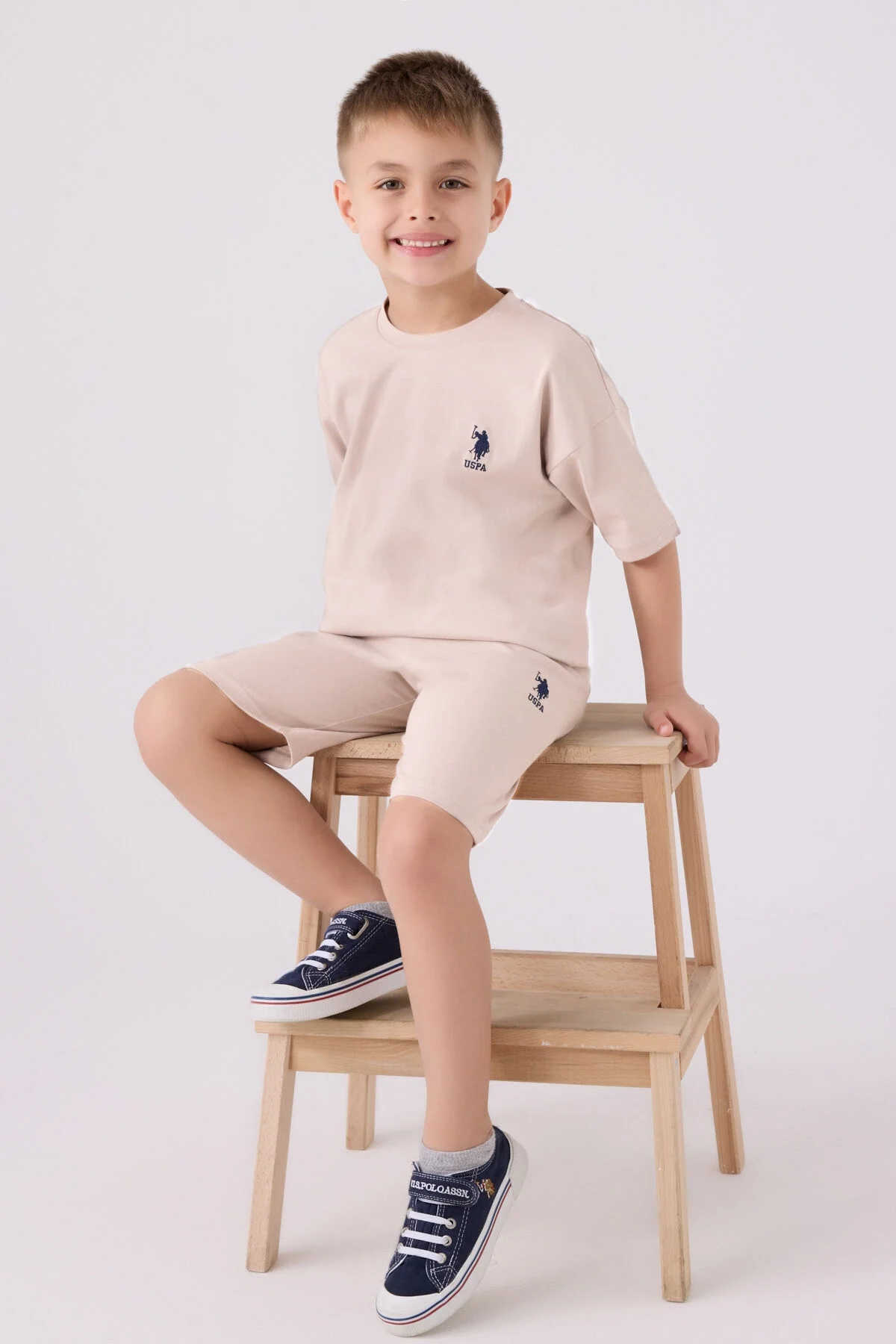 Krem renkli U.S. Polo Assn erkek çocuk Bermuda takım elbette, ön ve yan detaylı, marka logosu ile çocuk giyim
