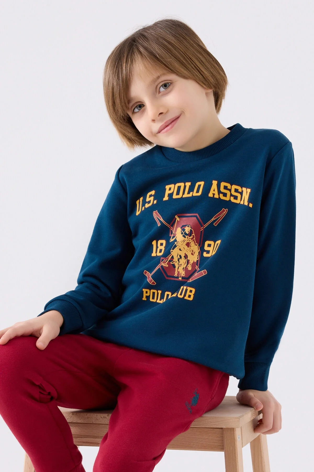U.S. Polo Assn Erkek Çocuk Lacivert Eşofman Takımı, koyu mavi üst ve kırmızı pantolon, çocuk giyim, marka logosu, model pozisyonu