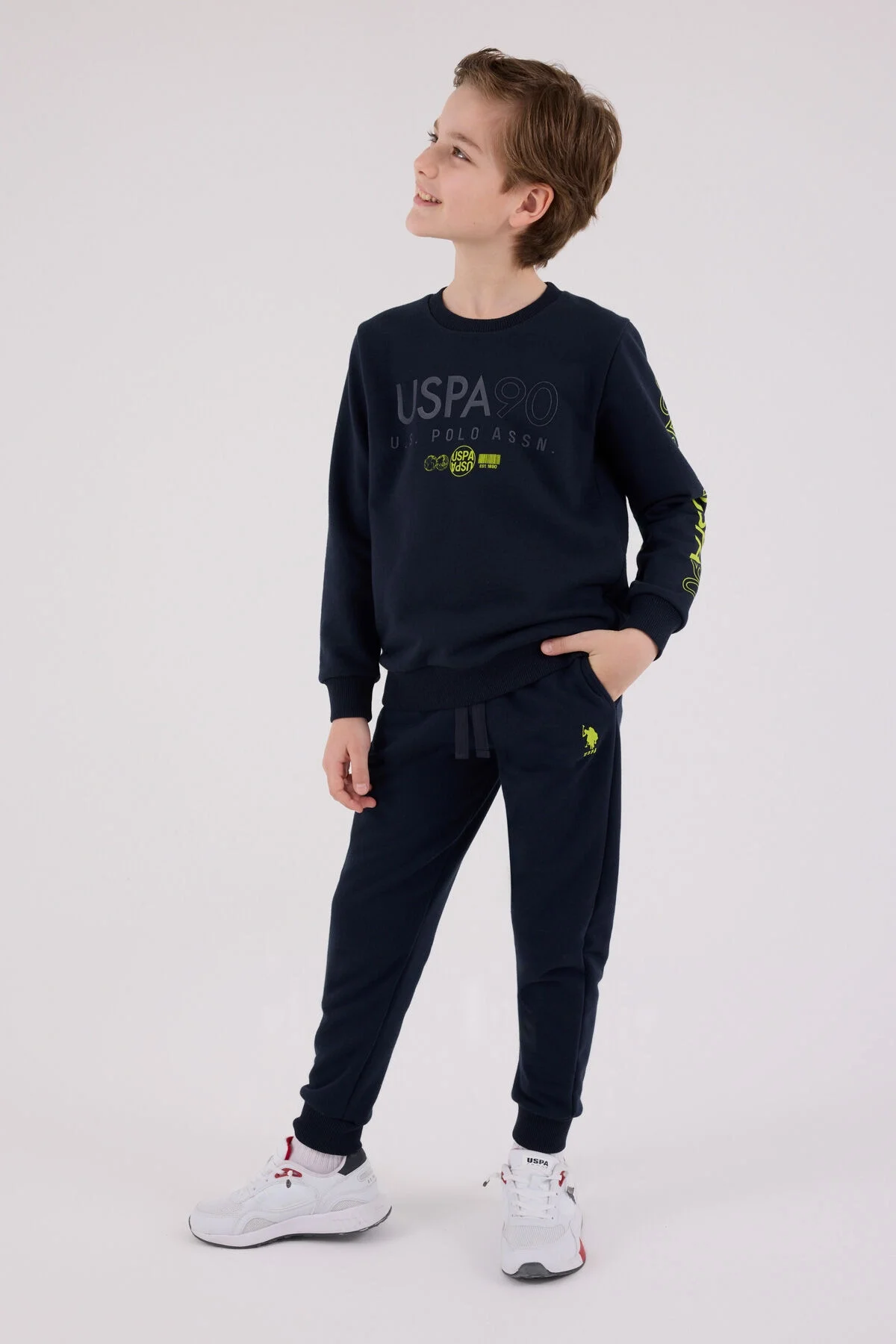 Lacivert USP90 desenli erkek çocuk eşofman takımı, U.S. Polo Assn marka, model pozisyonu, beyaz arka plan