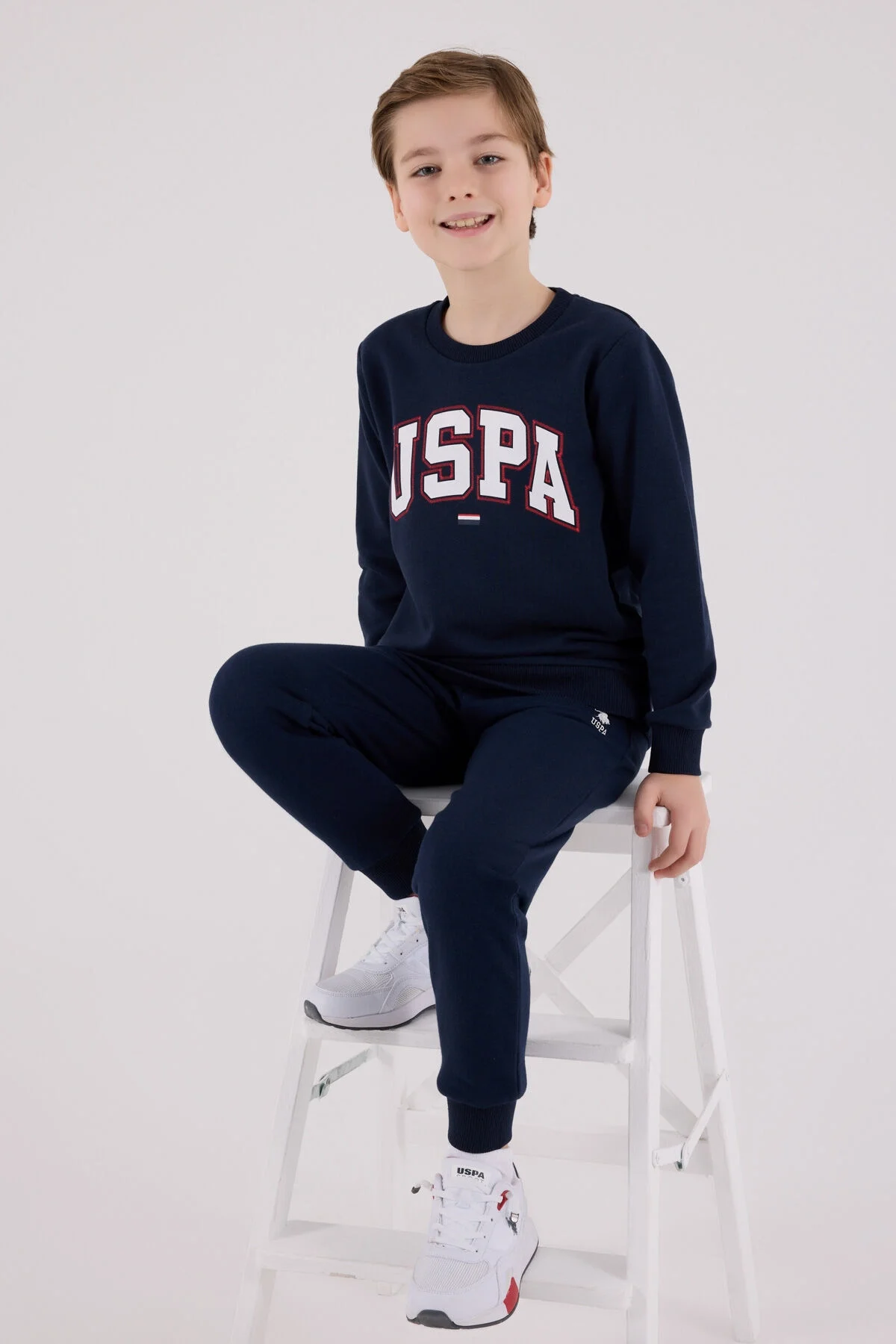 U.S. Polo Assn erkek çocuk lacivert eşofman takımı, USPA logosu, spor stil, çocuk giyim, beyaz spor ayakkabılarla
