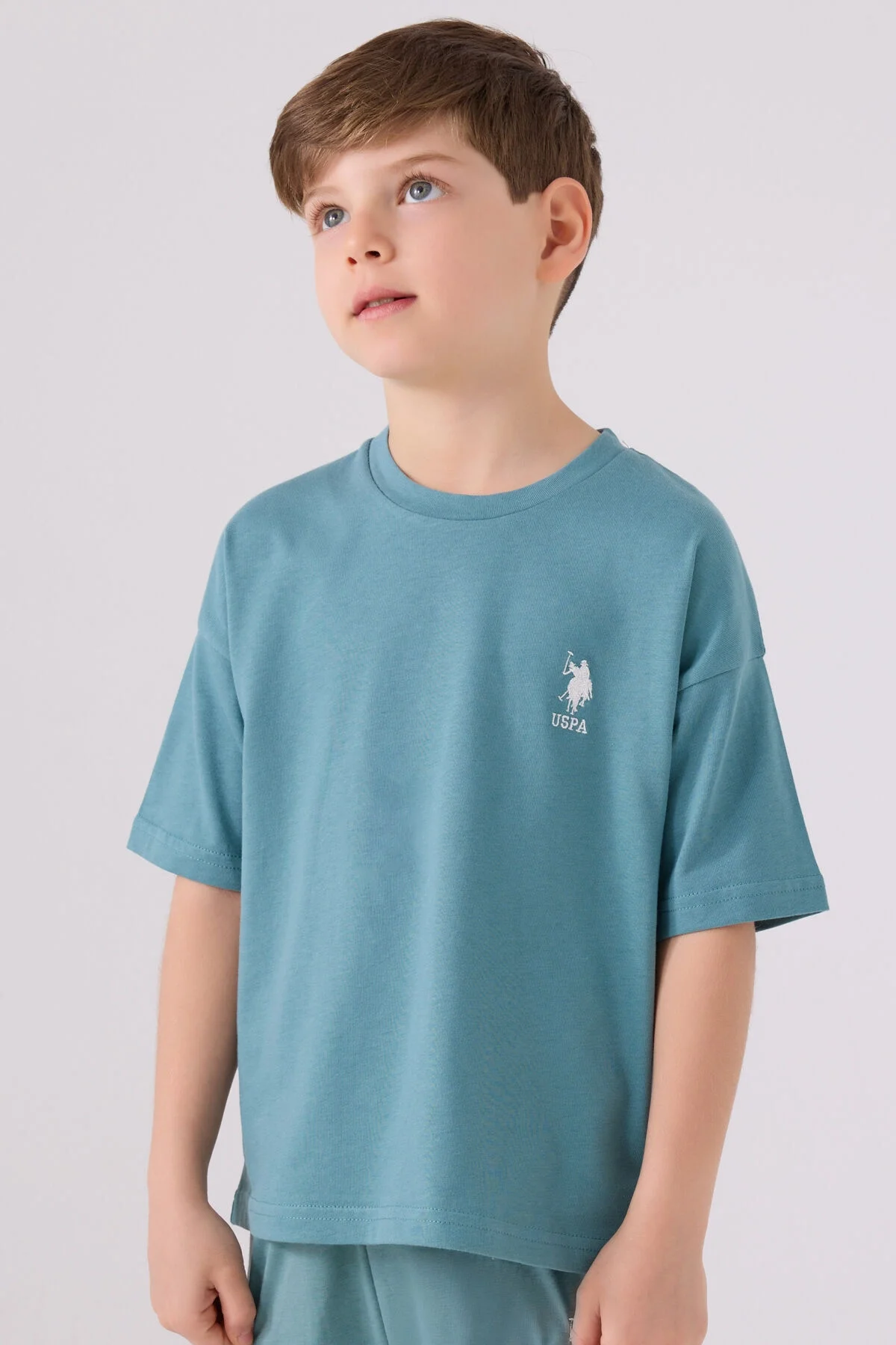 Mavi U.S. Polo Assn erkek çocuk Bermuda takım elbette, model pozisyonuyla tam görünüm, marka logosu ve günlük giyim tarzı