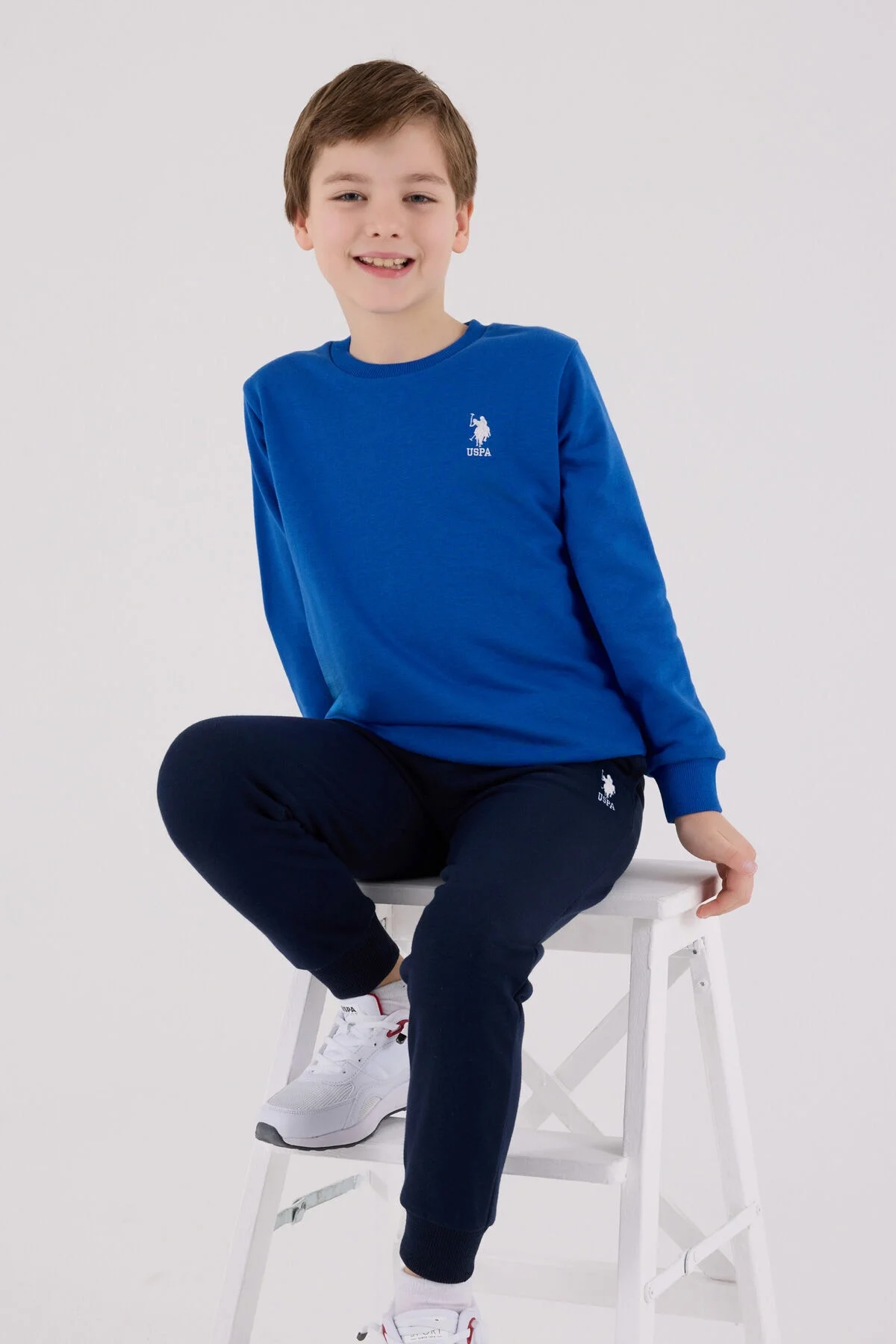 Mavi USP Polo Assn erkek çocuk eşofman takımı, kıyafet seti, spor ve günlük giyim, model pozisyonu, marka logosu