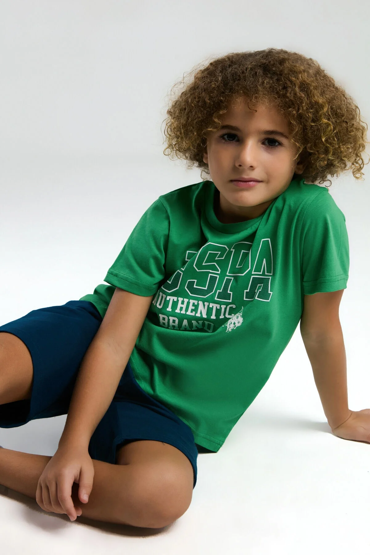 Yeşil USPA markalı erkek çocuk t-shirt, 'Authentic Brand' yazısı ve at logoyu, beyaz arka plan üzerinde