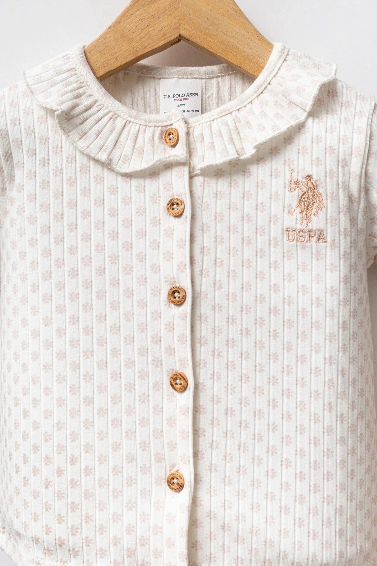 Beyaz desenli kıyafet ve pembe pantolonlu U.S. Polo Assn kız bebek takım elbette, marka bebek takımı