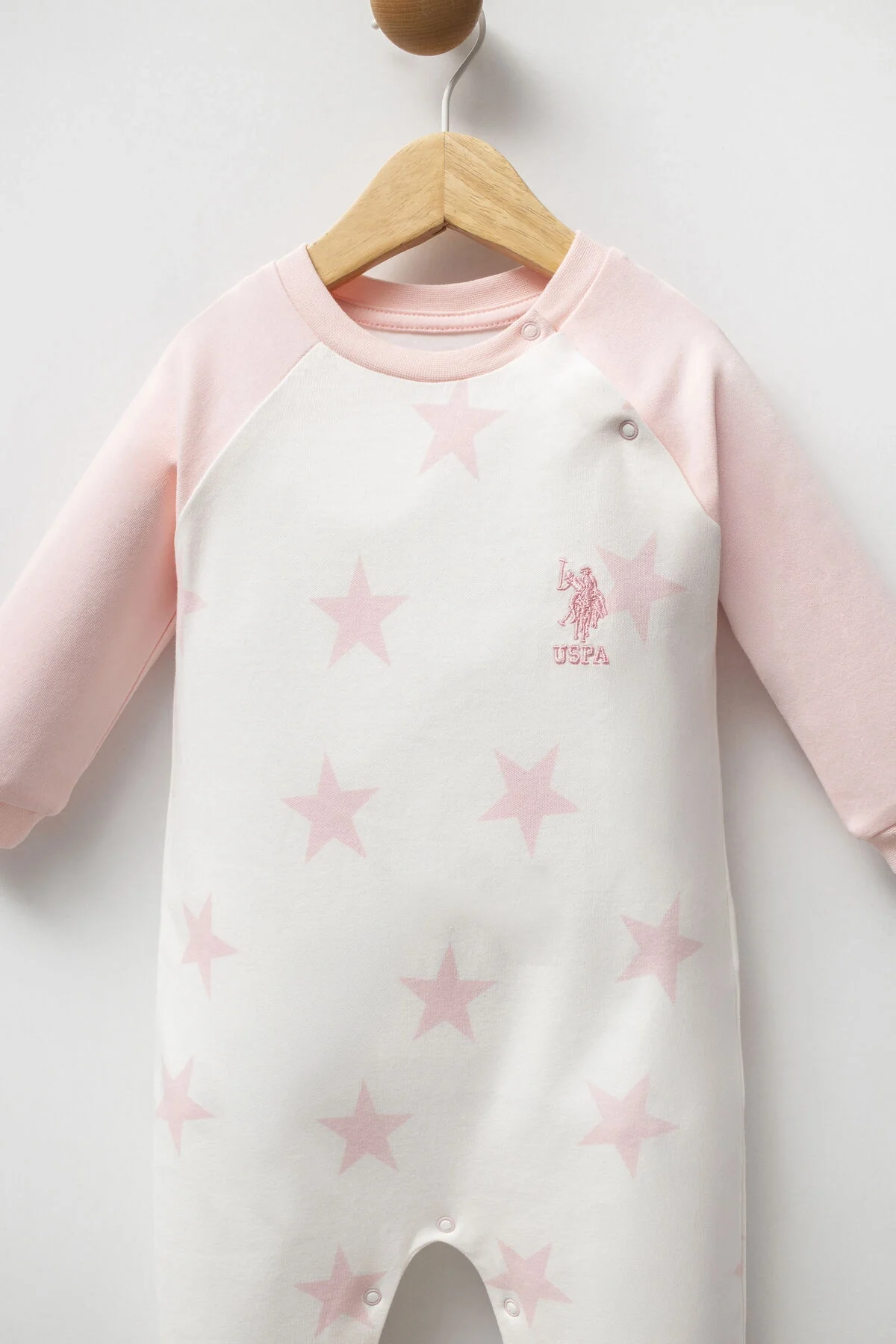 Beyaz yıldızlı, pembe kollu U.S. Polo Assn kız bebek tulumu, ön görünüm, marka logosu, düğme detayı