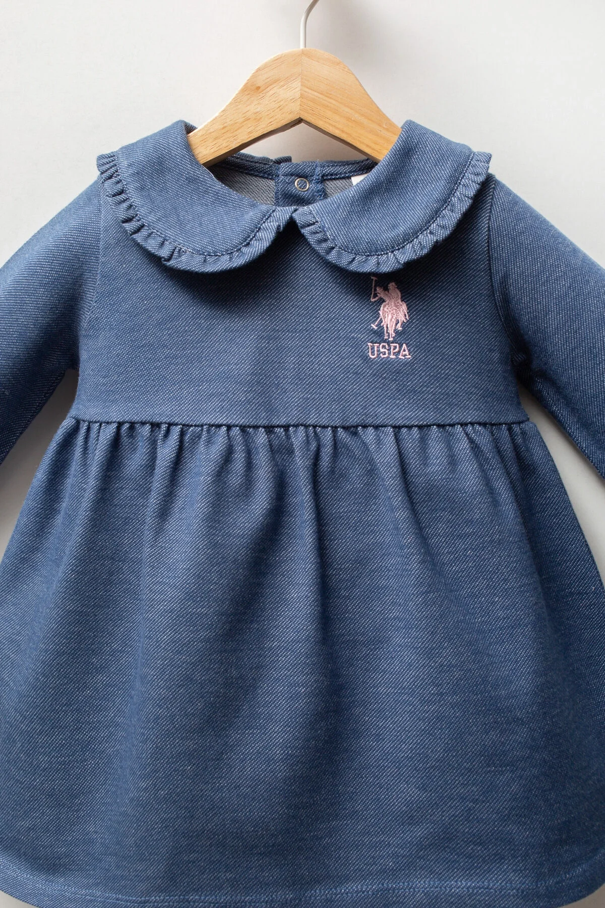 Mavi U.S. Polo Assn kız bebek elbisesi, kolları geniş, yaka detaylı, marka logosu ön tarafında, bebek elbiseleri kategorisinde