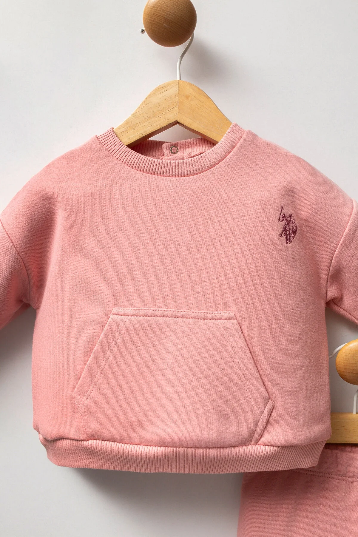 Pembe U.S. Polo Assn kız bebek takım elbette, yumuşak kumaşlı, ön cepleri ve marka logosuyla, bebek giyim seti