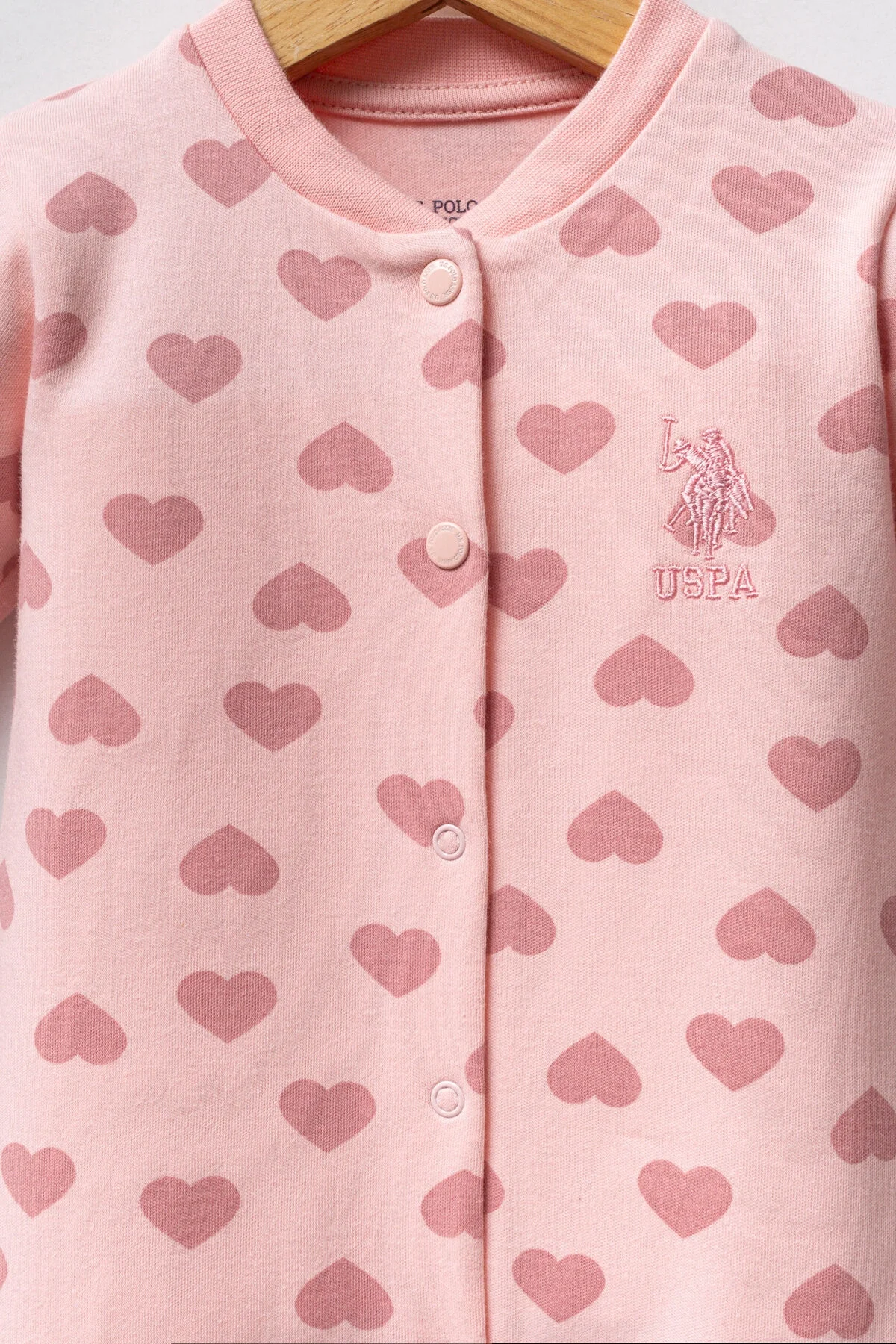Pembe kalp desenli U.S. Polo Assn kız bebek tulumu, ön düğme ve ayaklık, marka logosu ile bebek giyim