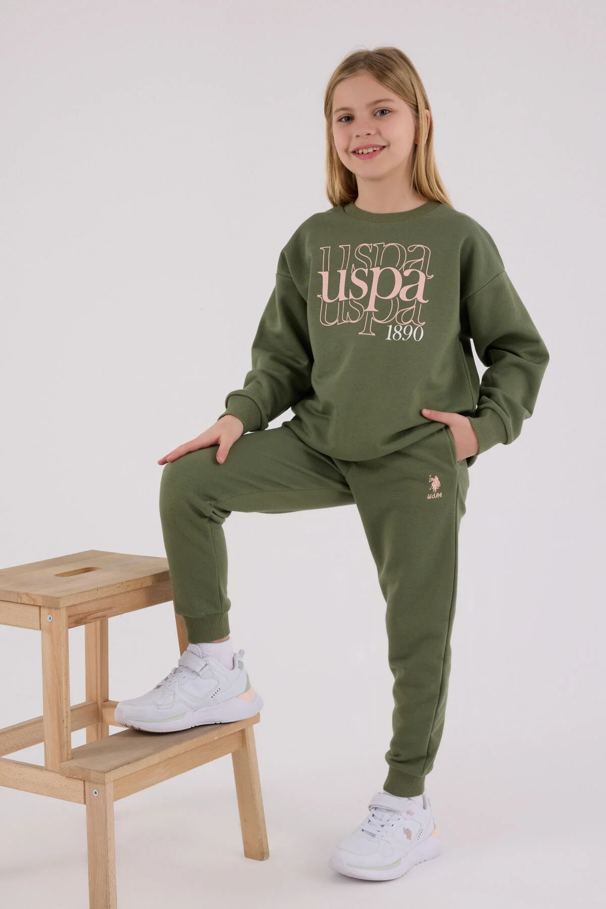 Haki renkli U.S. Polo Assn kız çocuk eşofman takımı, üstte 'USPA 1890' yazısı, pantolonun ön cebi ve bel çapı detaylı