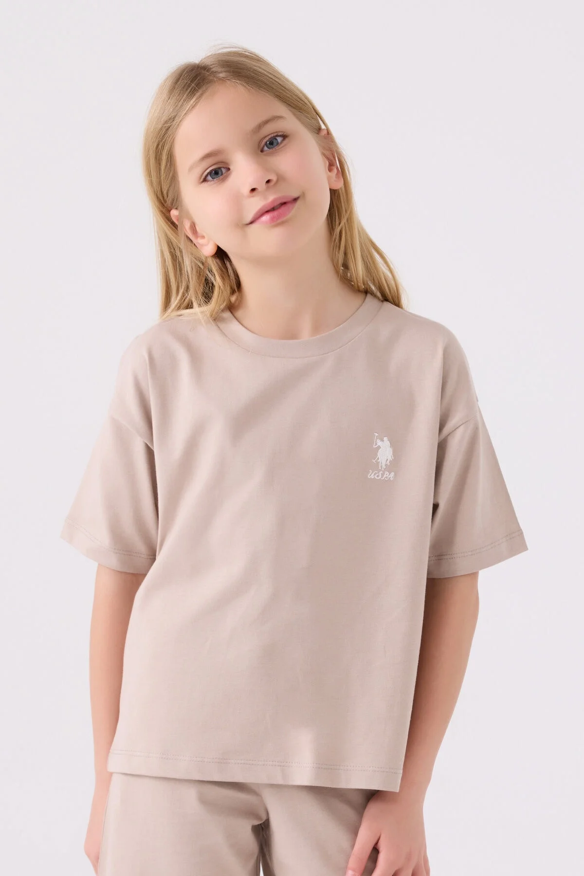 Krem renkli U.S. Polo Assn kız çocuk Bermuda takım elbette, model pozisyonu ve marka logosu detaylı