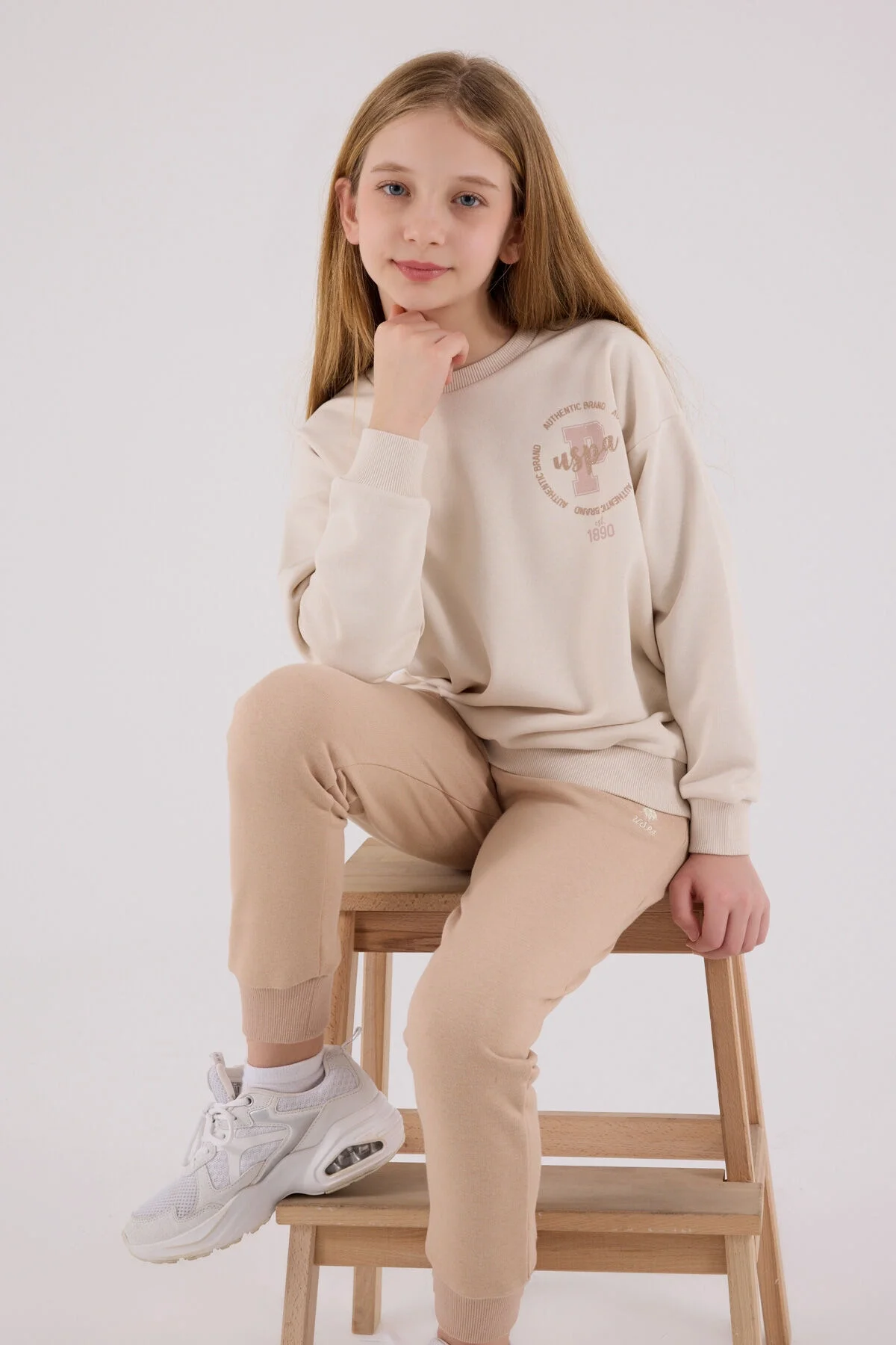 Krem renkli U.S. Polo Assn kız çocuk eşofman takımı, model ön görünüm, rahat günlük giyim stili