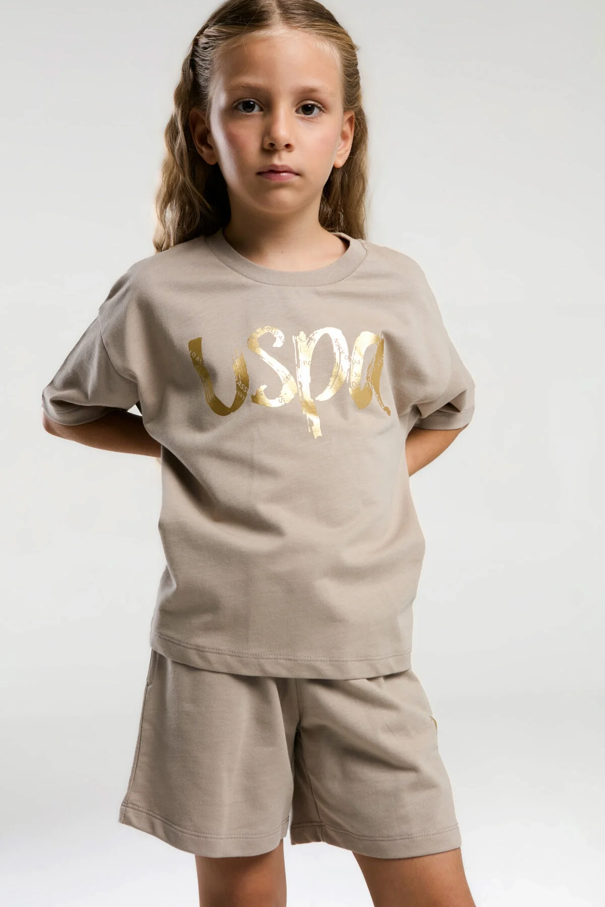 Krem renkli U.S. Polo Assn kız çocuk şort takım, altın logo, model ön görünüm, Arnetta markası