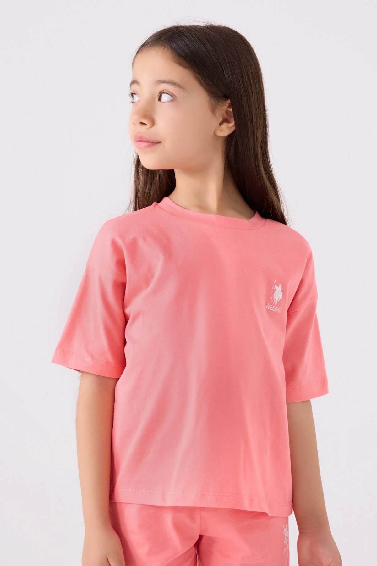 Pembe U.S. Polo Assn kız çocuk Bermuda takım seti, model pozisyonu, beyaz arka plan, marka logosu