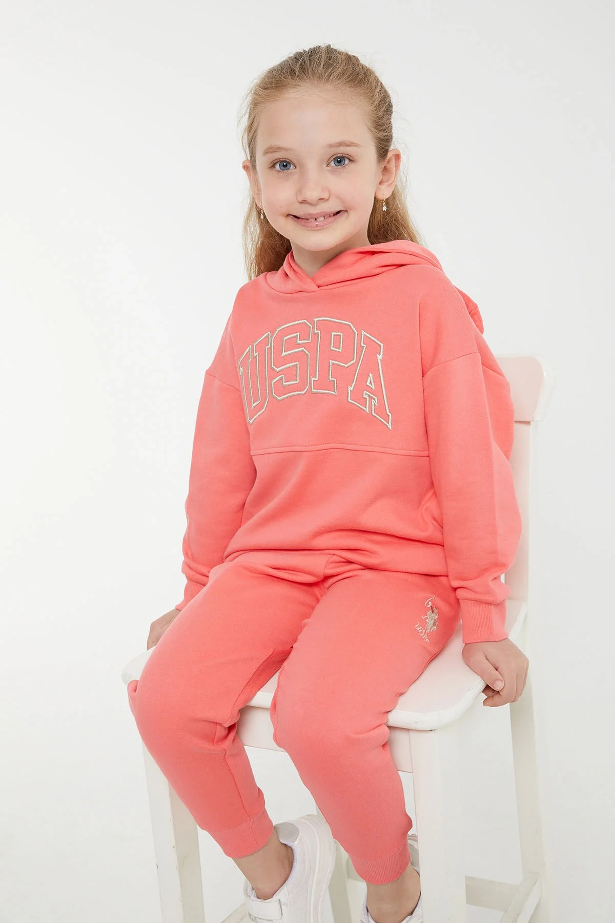 Pembe U.S. Polo Assn kız çocuk eşofman takımı, kapüşonlu üst ve pantolon, marka logosu, beyaz arka plan