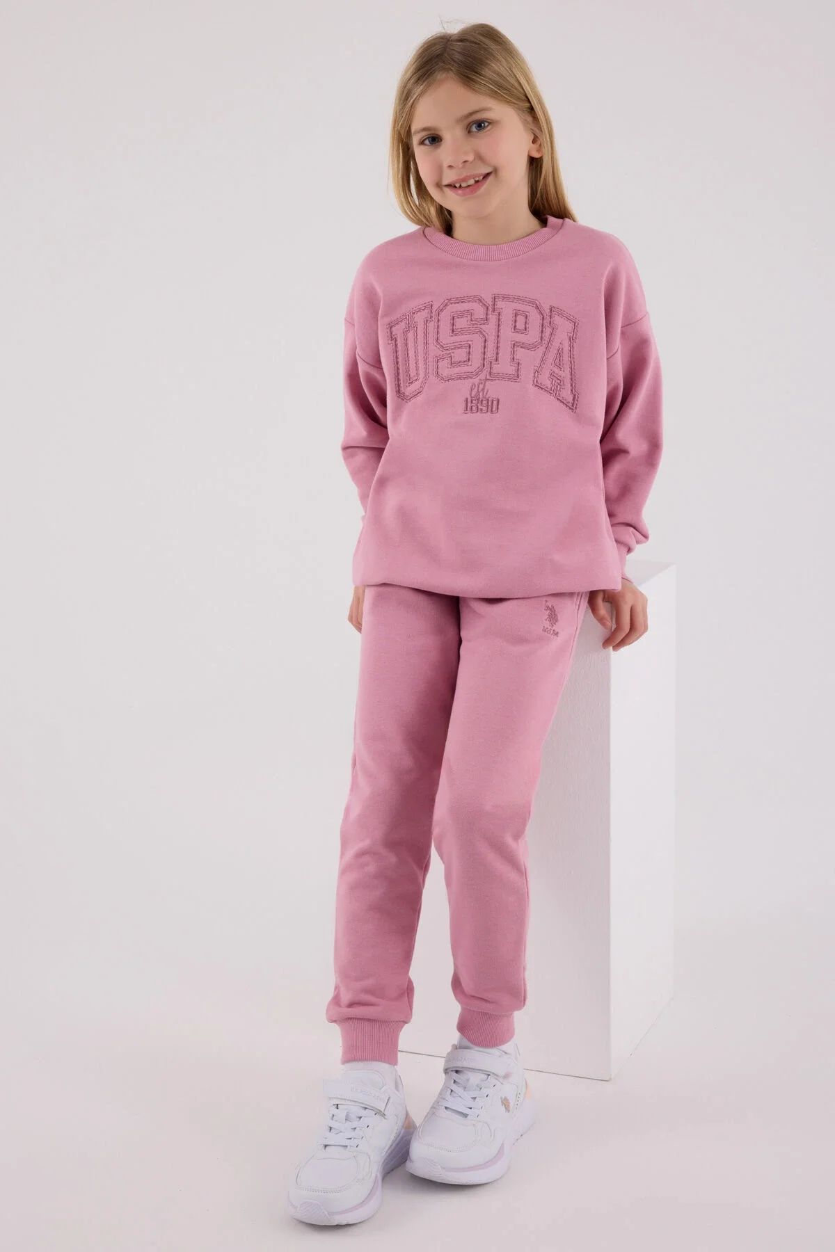 Pembe USPA marka kız çocuk eşofman takımı, spor stil, ön görsel, model pozisyonu, beyaz arka plan