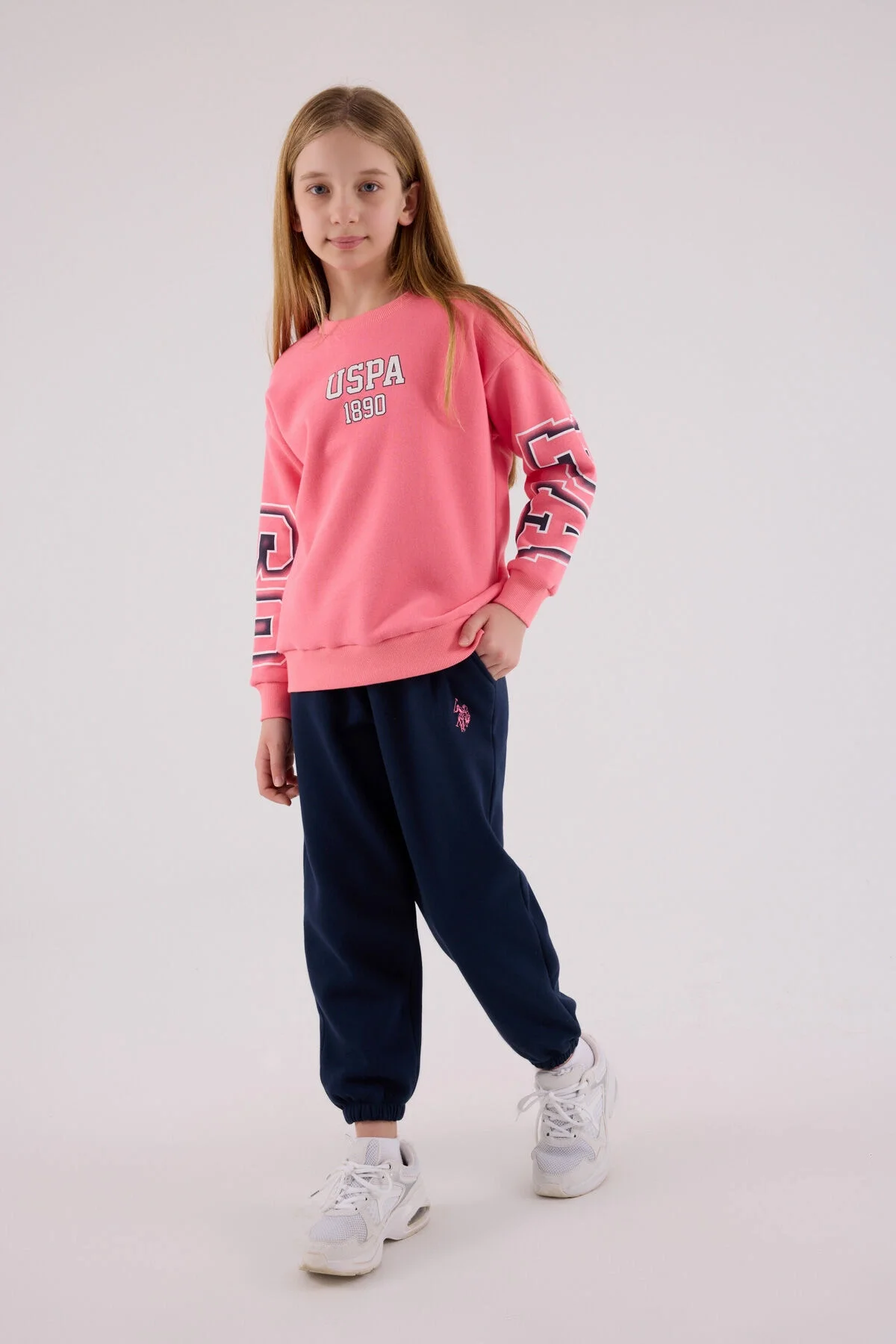 Pembe USPA 1890 yazlık eşofman takımı, kız çocuk modeli, koyu mavi pantolonlu, marka logolu, stüdyo çekim