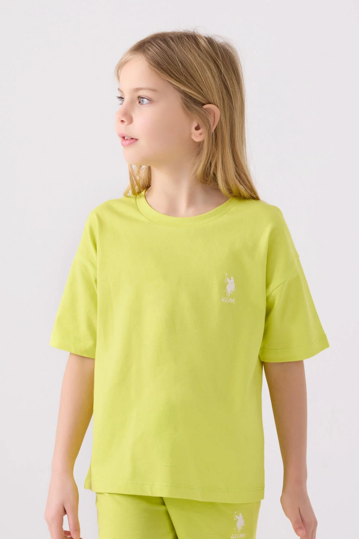 Sarı U.S. Polo Assn Kız Çocuk Bermuda Takımı, genç kız modeli, beyaz arka plan, üst ve alt birlikte