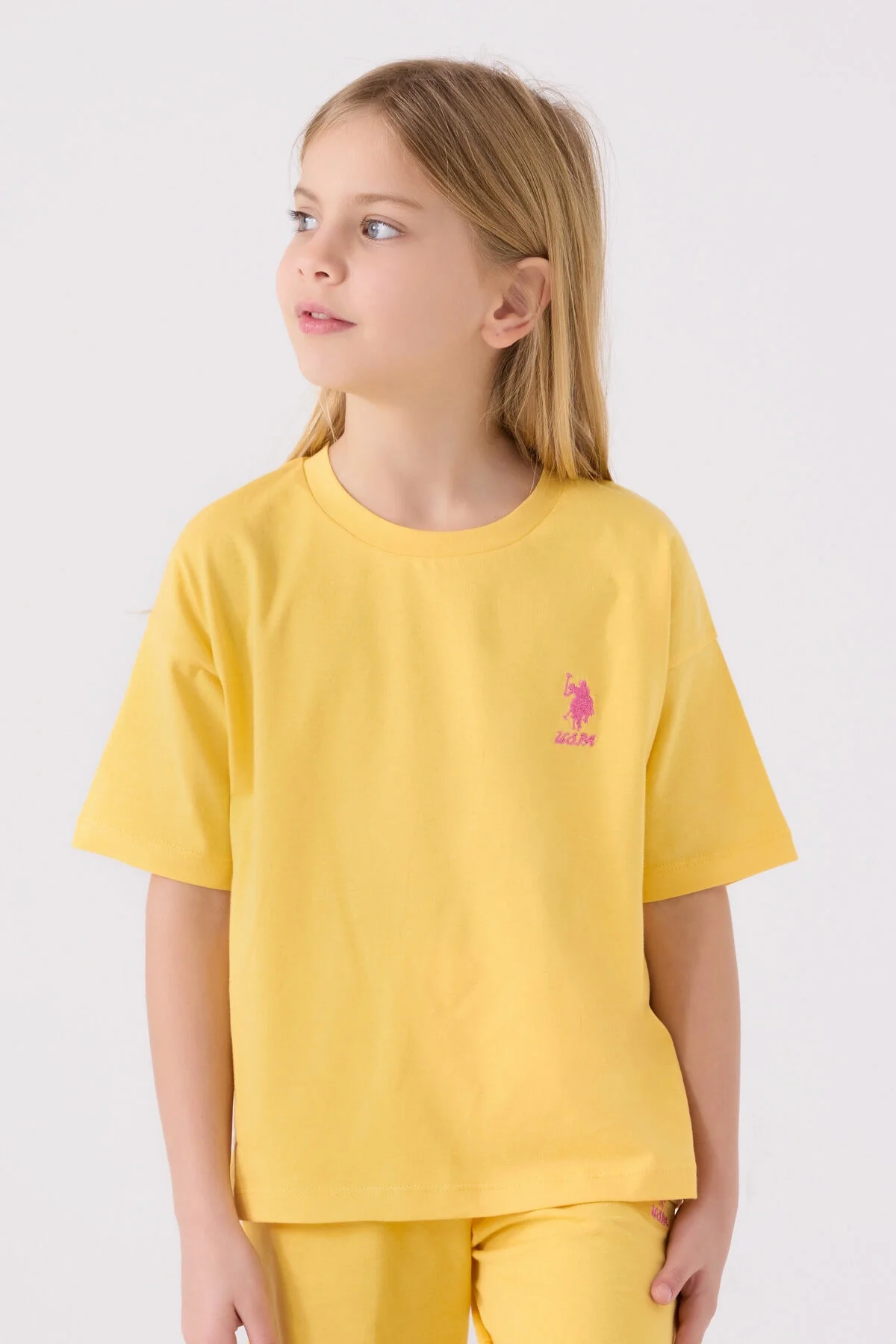 Sarı U.S. Polo Assn kız çocuk Bermuda takım seti, ön ve yan görünüm, marka logosu, beyaz ayakkabılarla takımlı