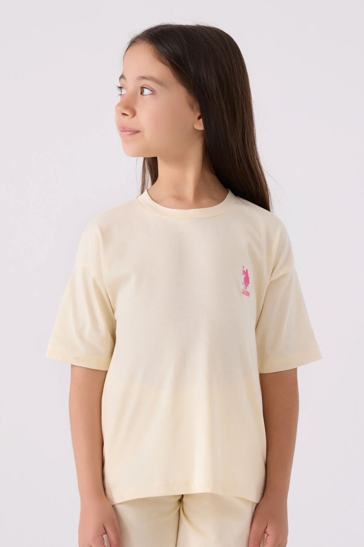 Sarı U.S. Polo Assn kız çocuk Bermuda takım, ön ve yan görünüm, pembe logo, beyaz spor ayakkabılarla takımlı