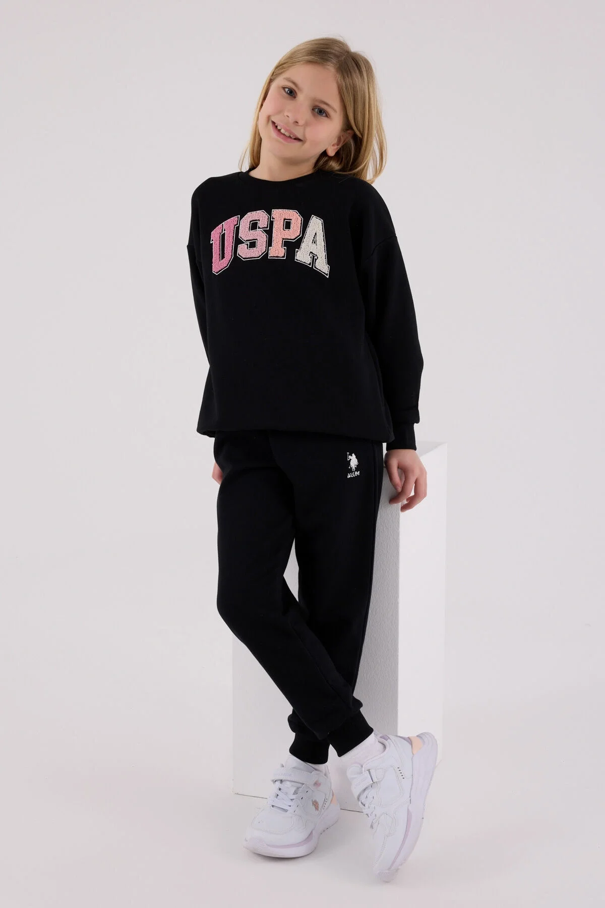 Kız çocuk siyah USPA eşofman takımı, spor stil, ön görünüm, model pozisyonu, beyaz arka plan