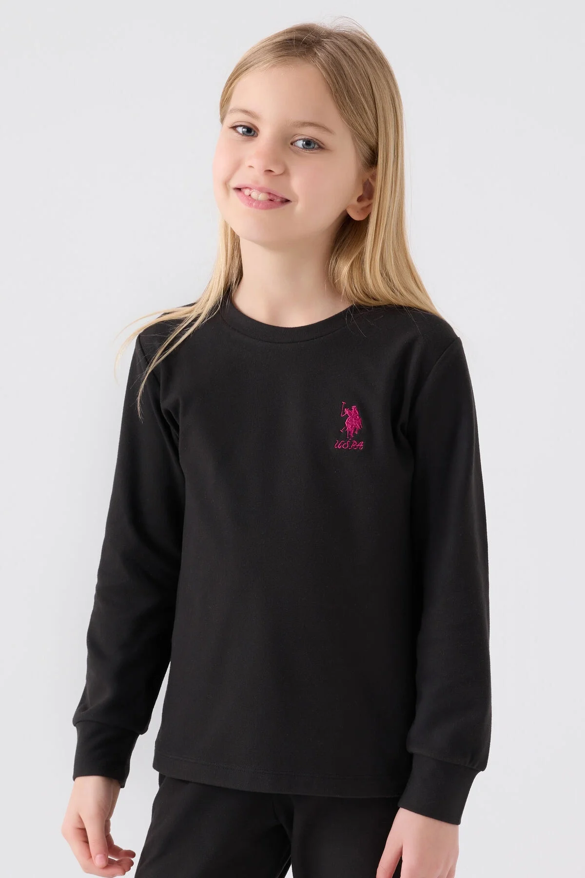Kız çocuk siyah U.S. Polo Assn pijama takımı, uzun kollu üst ve pantolon, ön göğüs üzerinde pembe logo, beyaz arka plan