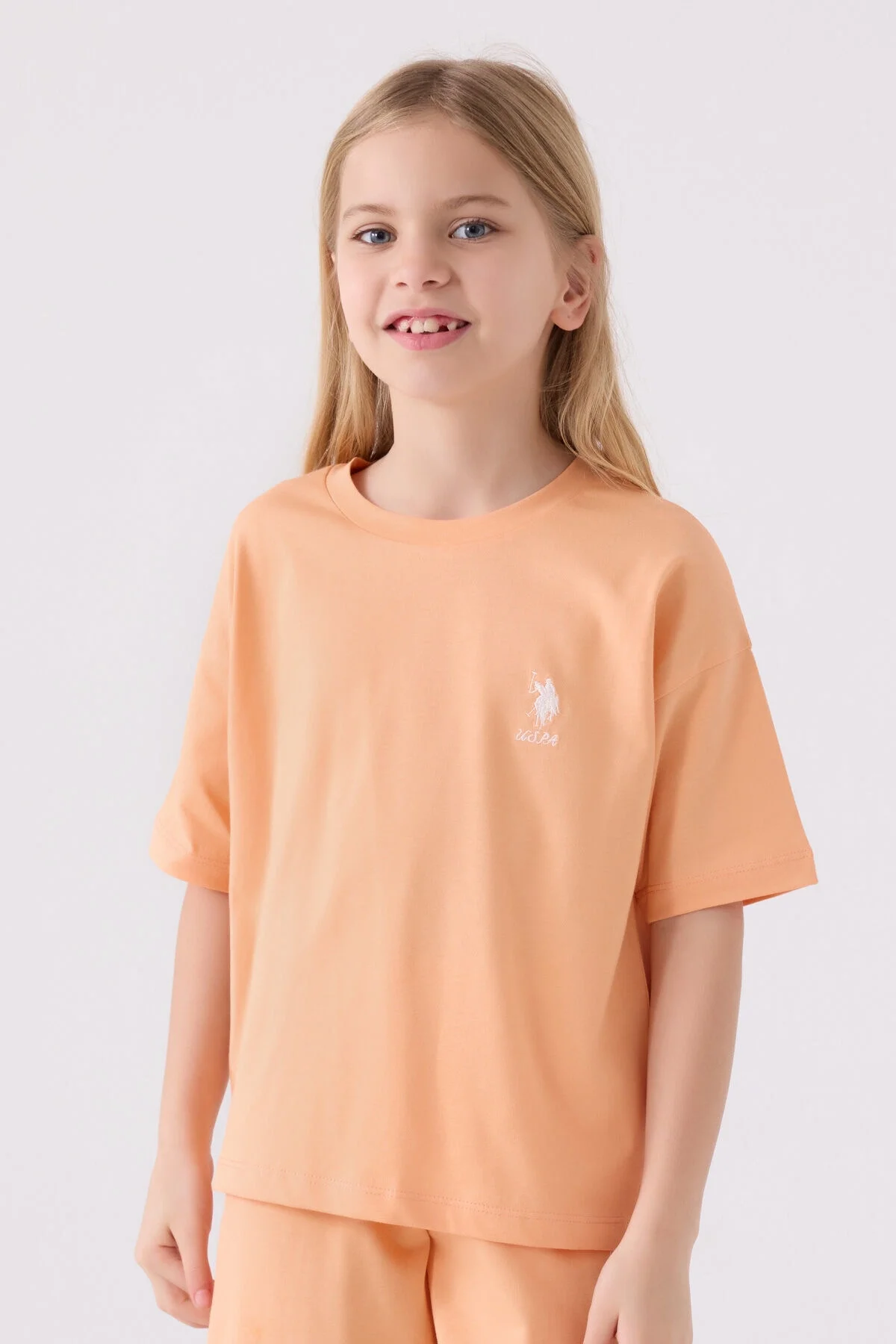 U.S. Polo Assn kız çocuk turuncu Bermuda takım, model ön görünüm, marka logosu, spor stil, yazlık giyim